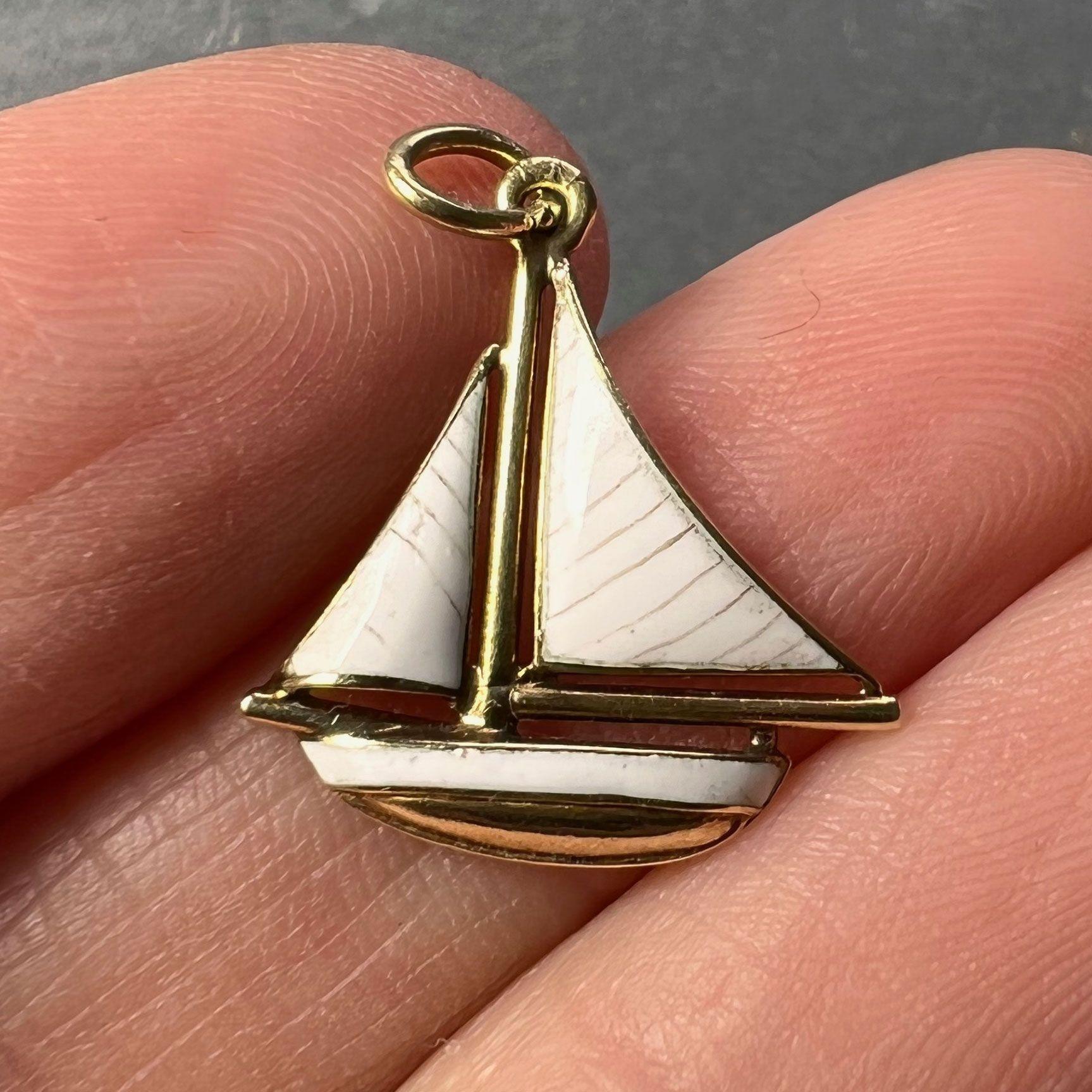 A 14 karat (14K) yellow gold charm pendant designed as a sailboat or yacht with white enamel sails and subtle brown stripe detail. Stamped 14K for 14 karat gold to the jump ring.

Dimensions: 1.6 x 1.5 x 0.2 cm (not including jump ring)
Weight: 0.88