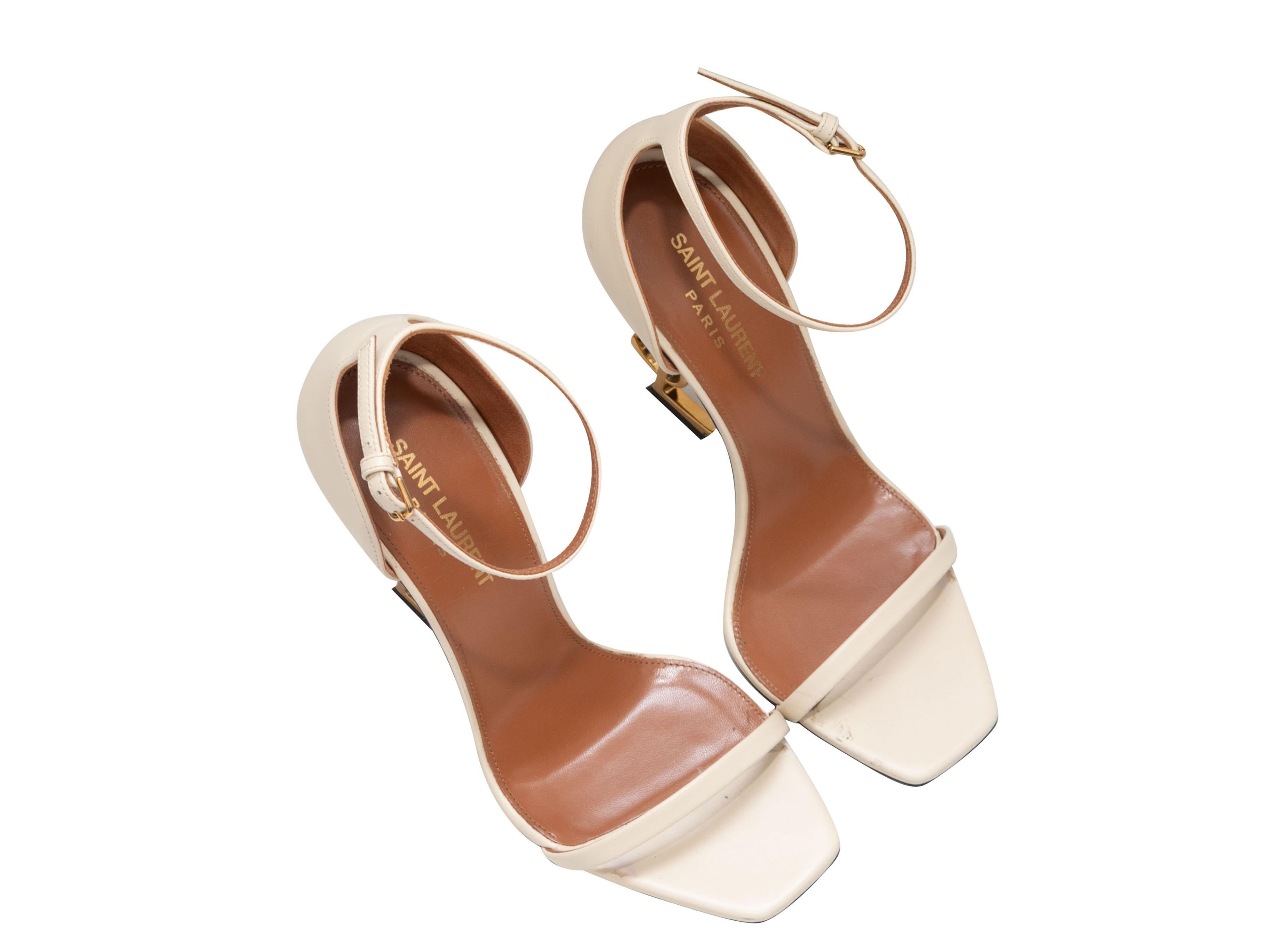 White leather Opyum ankle strap heeled sandals by Saint Laurent. Gold-tone logo heels. Buckle closures at ankle straps. 4
