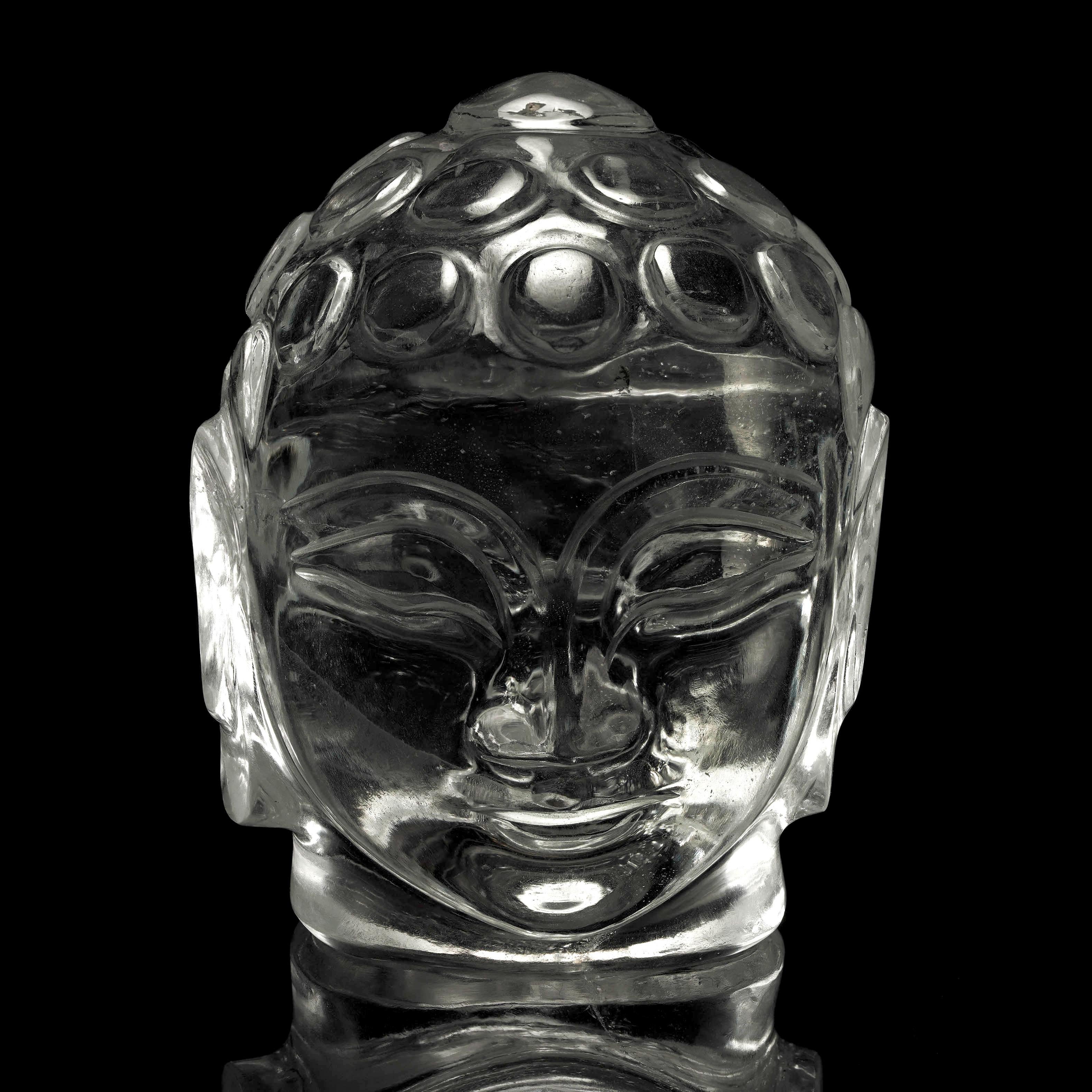 Cette exquise sculpture de tête de bouddha en saphir blanc de l'Inde incarne la sérénité et l'élégance. Sculpté avec une précision exceptionnelle, l'éclat cristallin du saphir rayonne d'une présence apaisante, ce qui en fait une pièce maîtresse