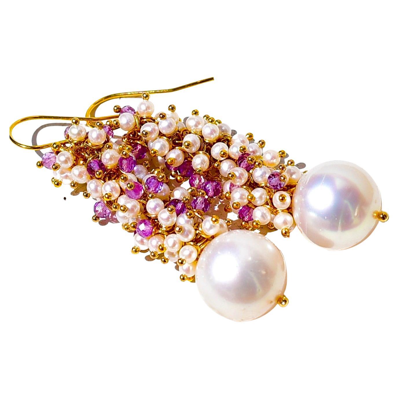 A beautifully iridescent pair of white South Sea cultured pearl has been crowned with shiny lavender amethyst beads. This amazing design is accentuated by pairing the intricate earrings with simple 14K Yellow Gold ball end french hook ear wires.