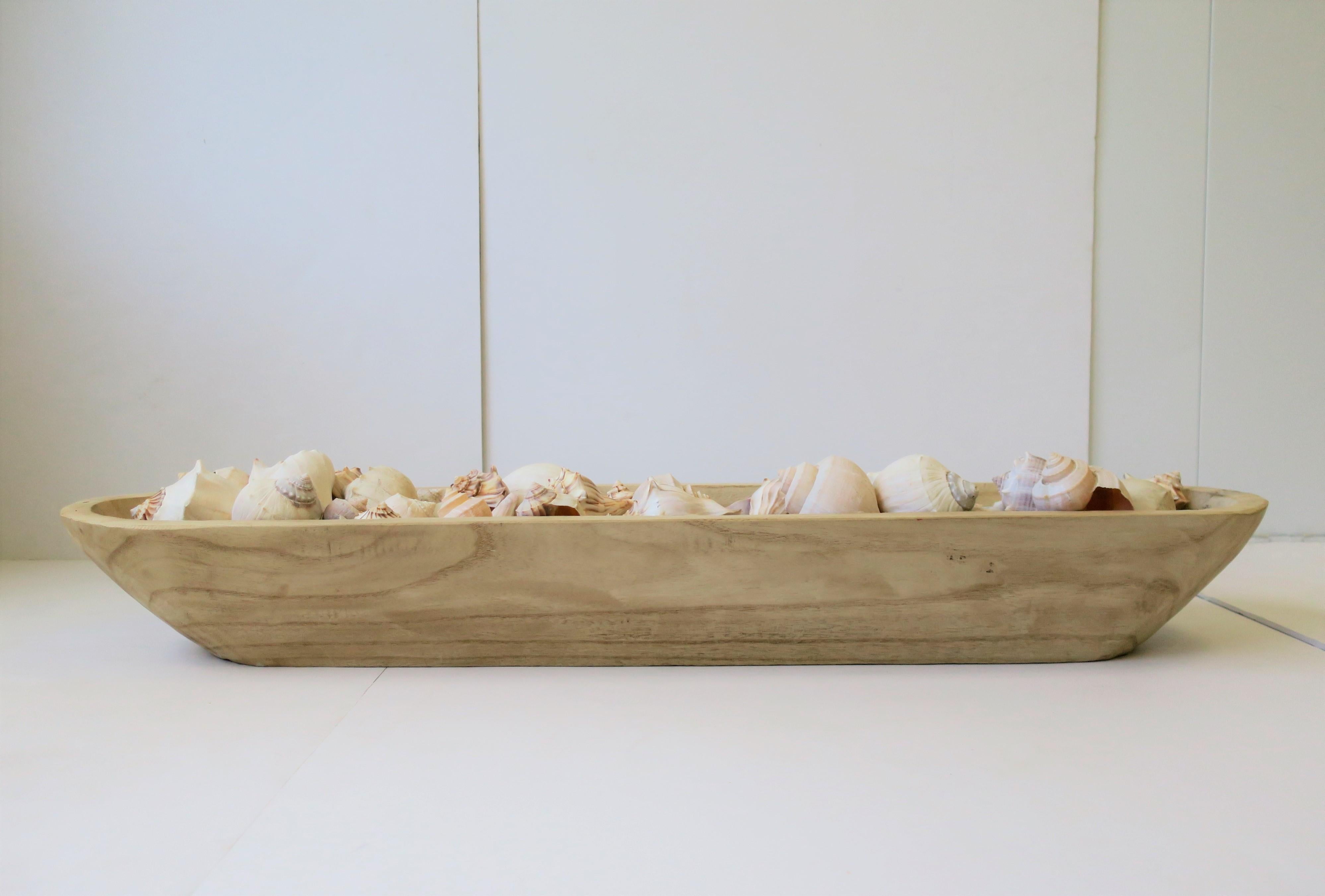 A very beautiful large grouping of all natural seashells. Vessel contains over 50+ matte white and tan/brown/off-white seashells in long/oblong hand-carved wood centerpiece. There are over 50 individual seashells in this rectangular hand-carved wood