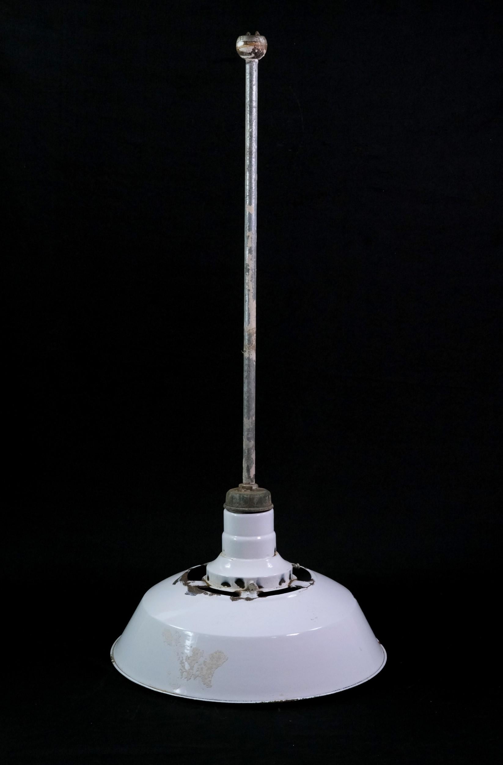 Mid-20th century industrial factory pendant light featuring a white enameled steel shade mounted to a steel pole and canopy. The shade has subtle black enamel around the bottom rim with moderate chipped paint. Small quantity available at time of