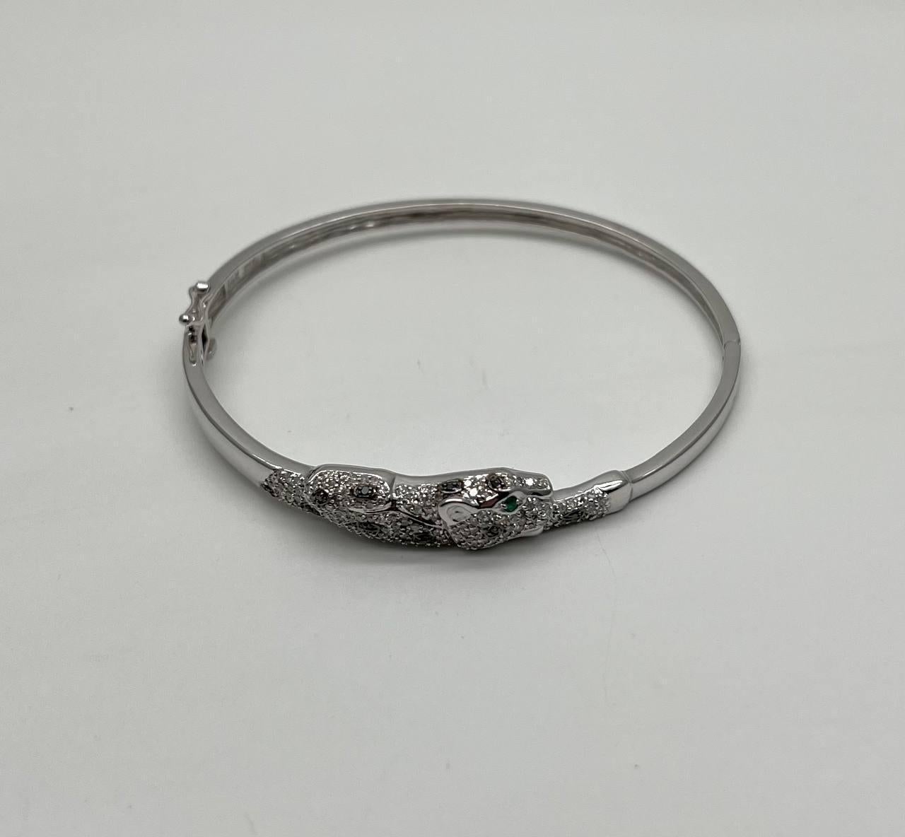 Ce bracelet exquis. La pièce maîtresse est un motif de panthère finement détaillé, incrusté de diamants étincelants. Les yeux de la panthère sont sertis d'émeraude d'un vert éclatant, ajoutant un contraste saisissant. Or blanc 14K. 1,03 ct de