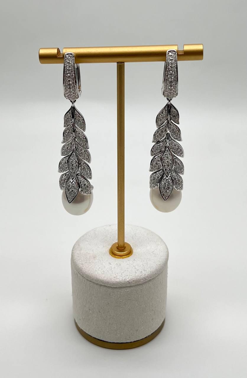 Ces boucles d'oreilles sophistiquées sont fabriquées avec précision et style.

Chaque boucle d'oreille présente une série de segments en forme de feuilles, minutieusement ornés de diamants blancs étincelants de 3,5 ctw.

Les segments cascadent
