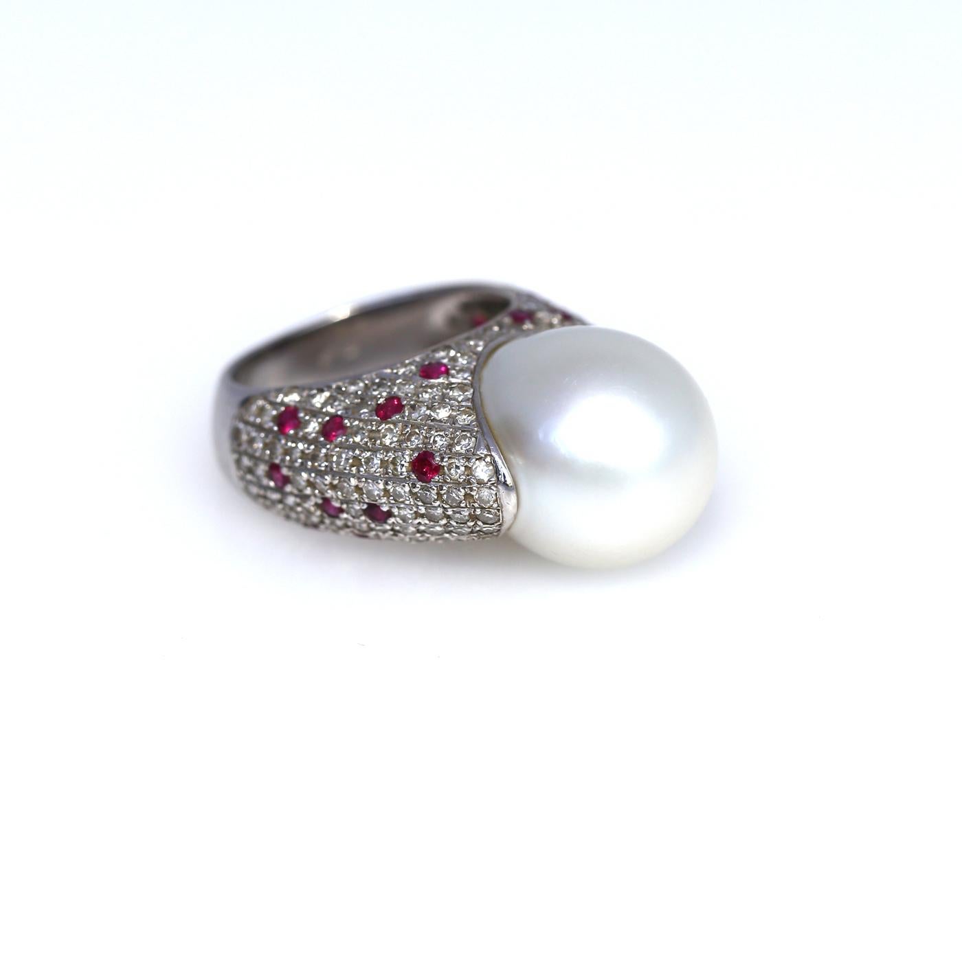 15 mm White South Sea Pearl Ring with round-cut Diamonds and Rubies. It is a fine item perfectly representing the era it was made in. 1980es are in fashion again. Bold designer decision. The Fine Pearl almost oval-shaped with 15mm in diameter. The