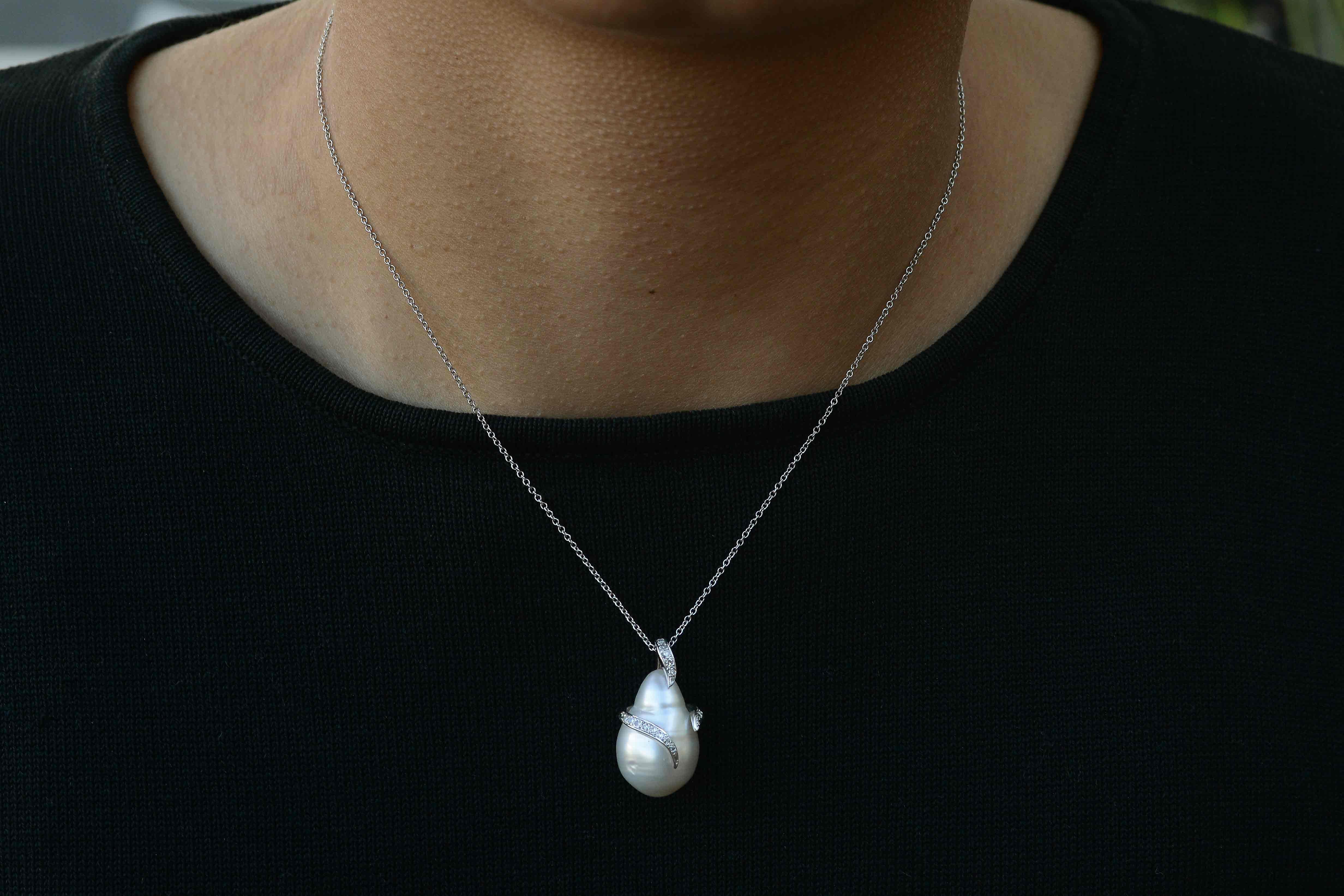 A lustrous and luminous white South Sea pearl pendant necklace. The large, teardrop shape baroque pearl shimmers seductively and has a diamond snake wrapped around it and is completed by a 14k white gold roll chain. So wearable and chic, you can