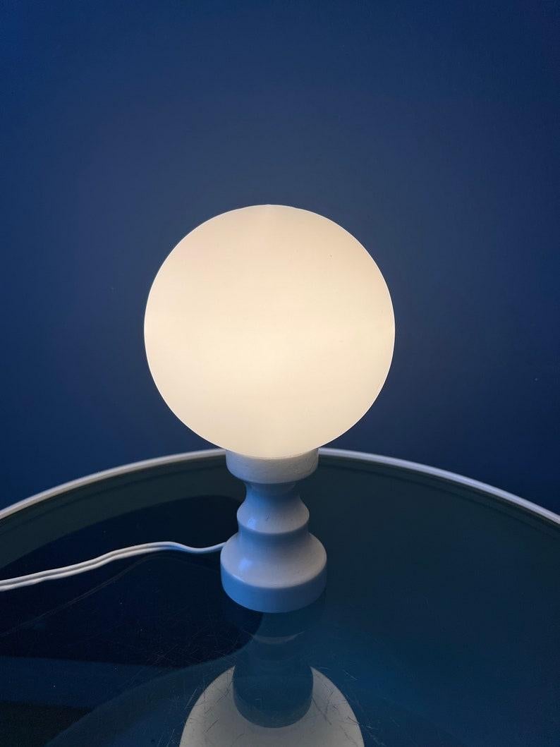 Lampe de bureau de l'ère spatiale avec abat-jour en verre opalin. La base est en bois et a une laque blanche. La lampe nécessite une ampoule E14 et dispose actuellement d'une fiche de connexion à l'UE.

Informations complémentaires :
Matériaux :
