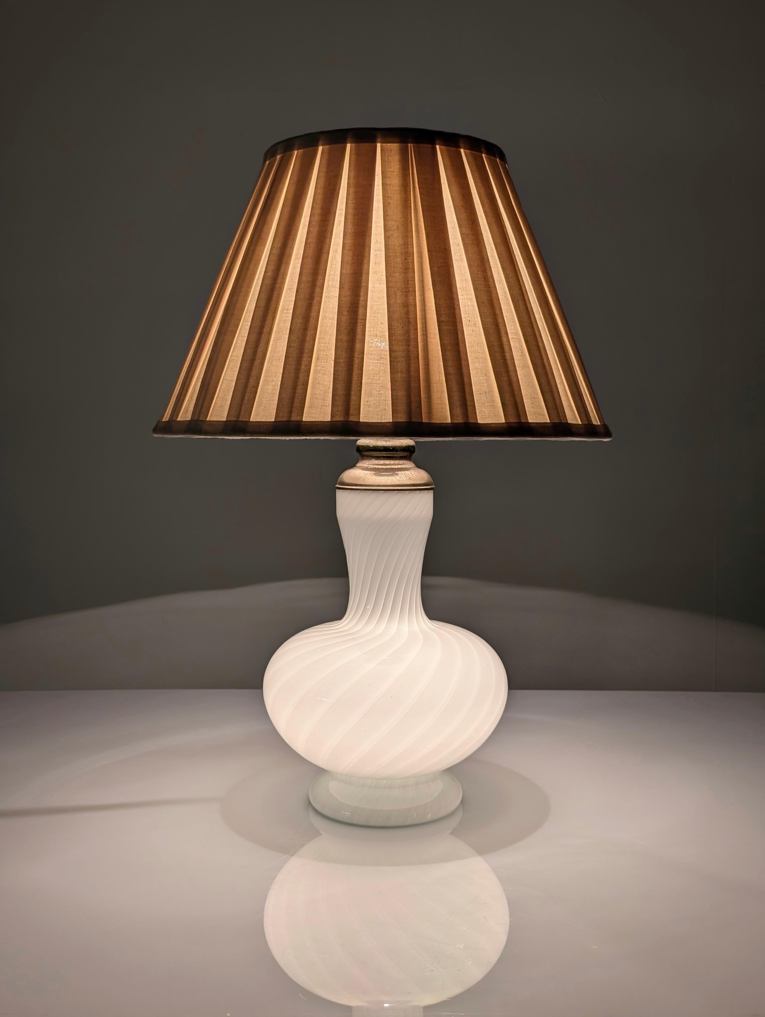 Italienische Tischleuchte aus feinem Murano-Glas mit zartem Spiraldesign im Stil der besten Venini-Kreationen, von zeitloser Eleganz. Diese elegante Leuchte ist mit einem dualen Beleuchtungssystem ausgestattet, bei dem sowohl die Innen- als auch die