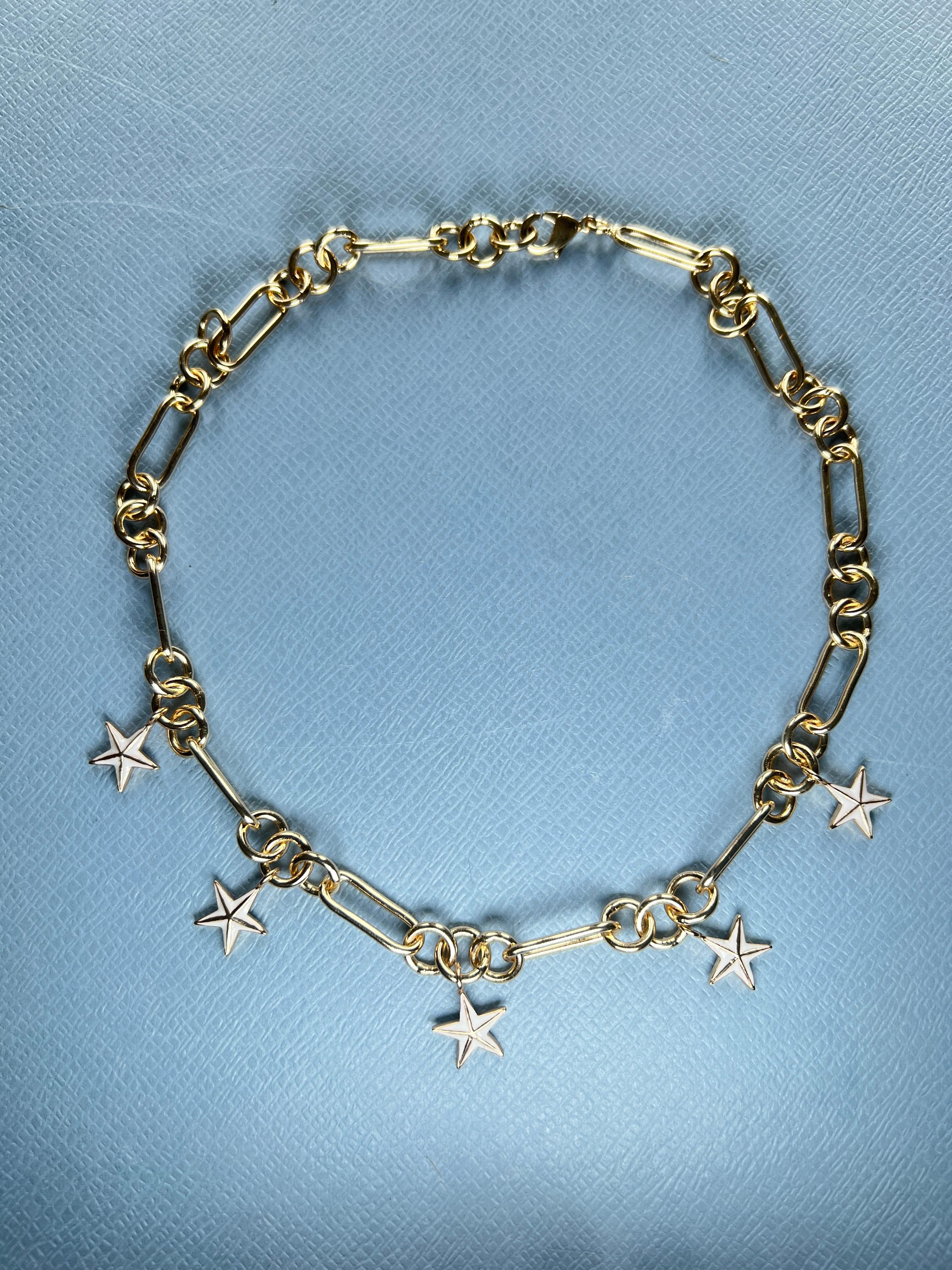 Collana a catena con ciondolo a 5 stelle in oro 14k con smalto bianco dipinto a mano su ogni stella.

La stella a cinque punte, spesso conosciuta come pentagramma, racchiude un importante simbolismo spirituale in diverse tradizioni e credenze. In