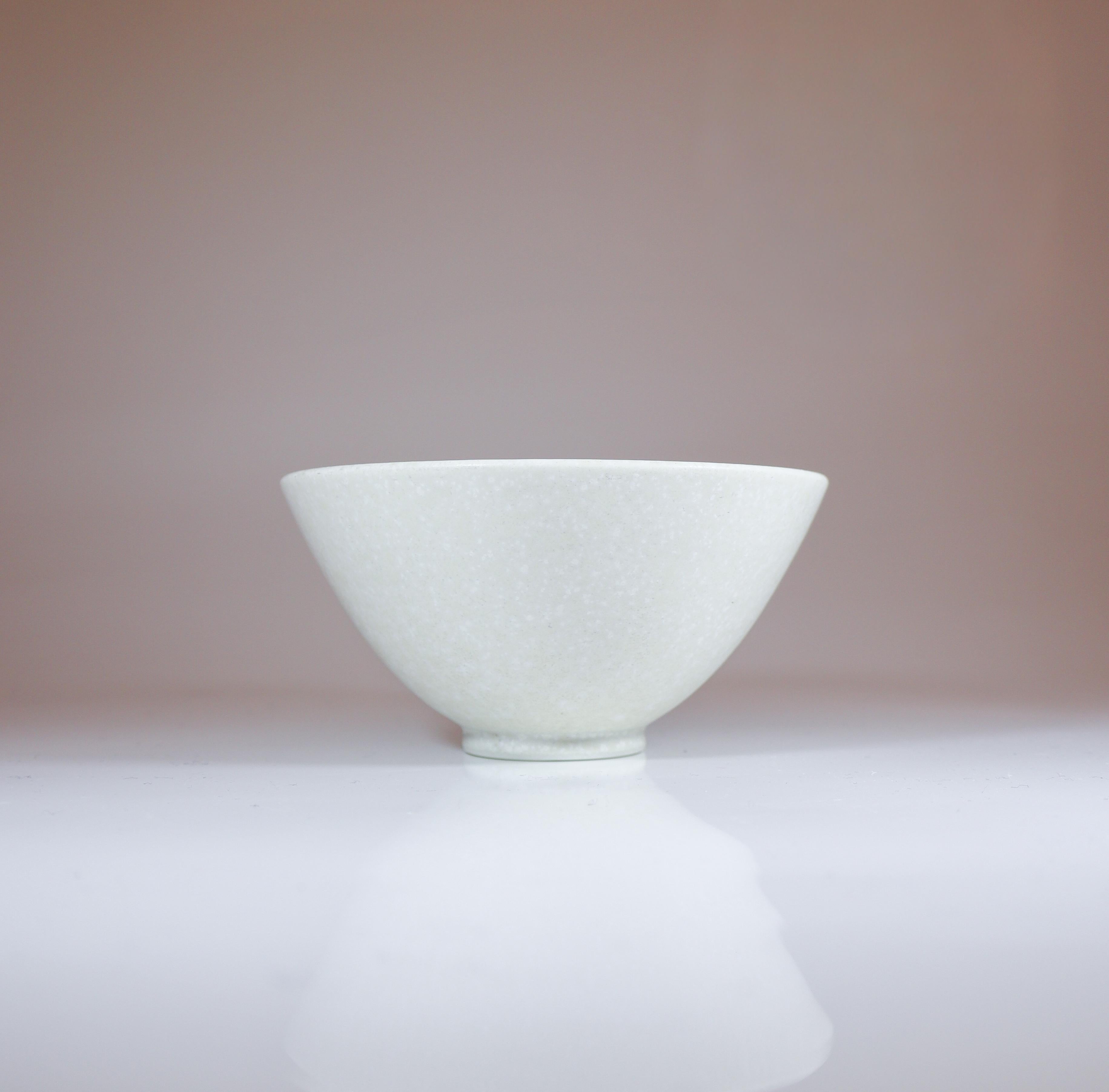 Una ciotola bianca e rotonda con un'incantevole smaltatura, disegnata da Gunnar Nylund di Rörstrand, alta 6,5 cm e con un diametro di 12,5 cm. È in ottime condizioni, contrassegnato come seconda qualità, probabilmente a causa di una piccola macchia