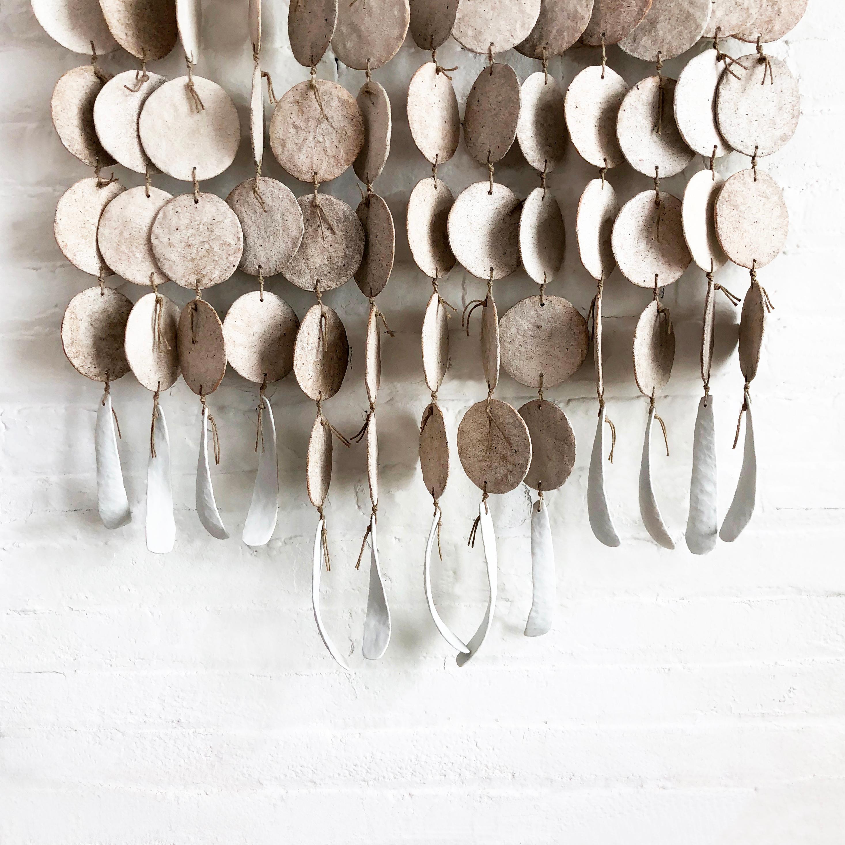 Pinched stoneware discs are knotted with waxed whipping twine. Each strand is assembled with polished hemp rope and a porcelain featherbone. The disc curtain hangs from a bevelled white oak or walnut bar. 

Curtain measures approximately 2' wide x