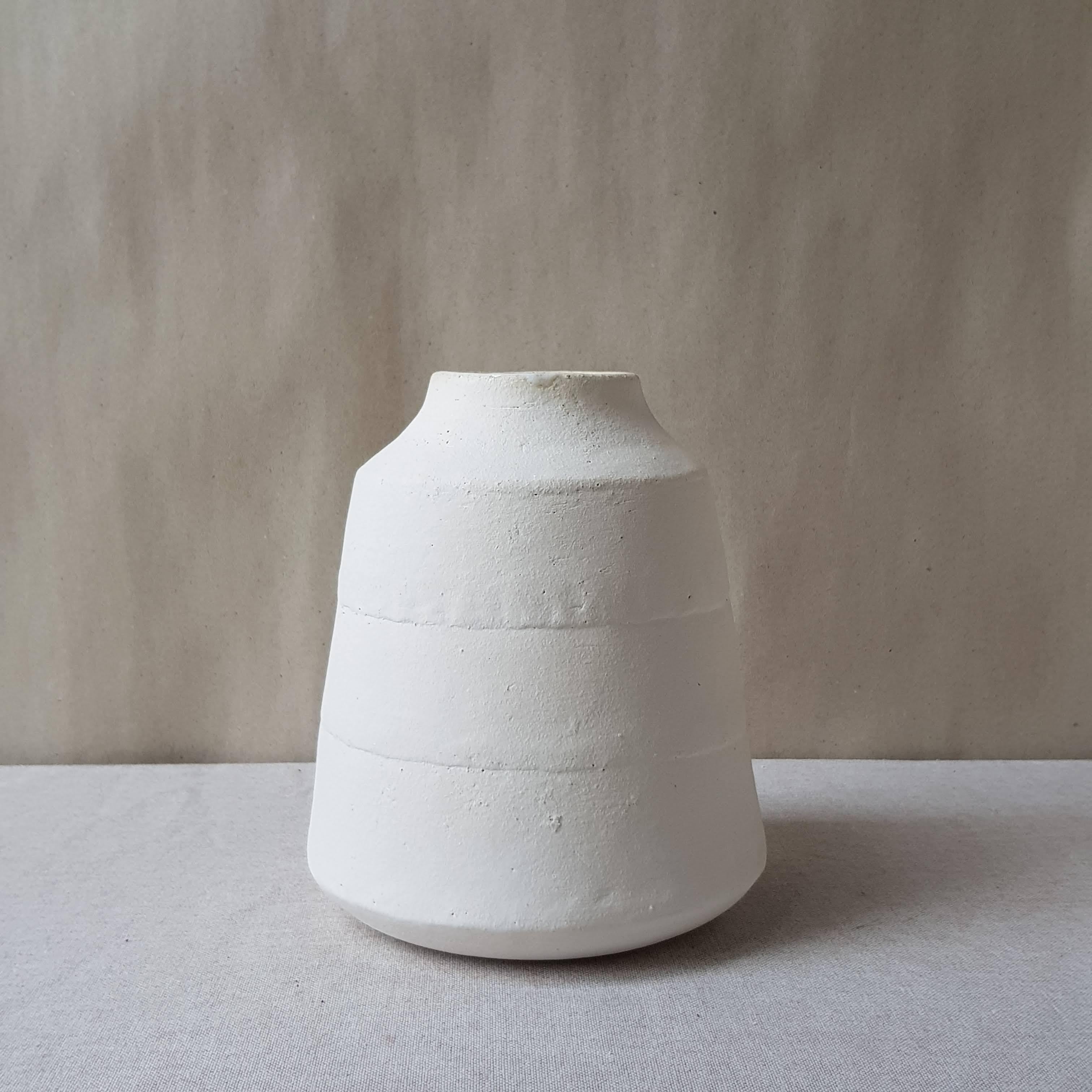 White Stoneware Kados Vase by Elena Vasilantonaki
Unique
Dimensions: ⌀ 30 x H 25 cm (Dimensions may vary)
Materials: Stoneware
Available finishes: Black, White, Grey, Brown, Red, White Patina

Growing up in Greece I was surrounded by pottery forms
