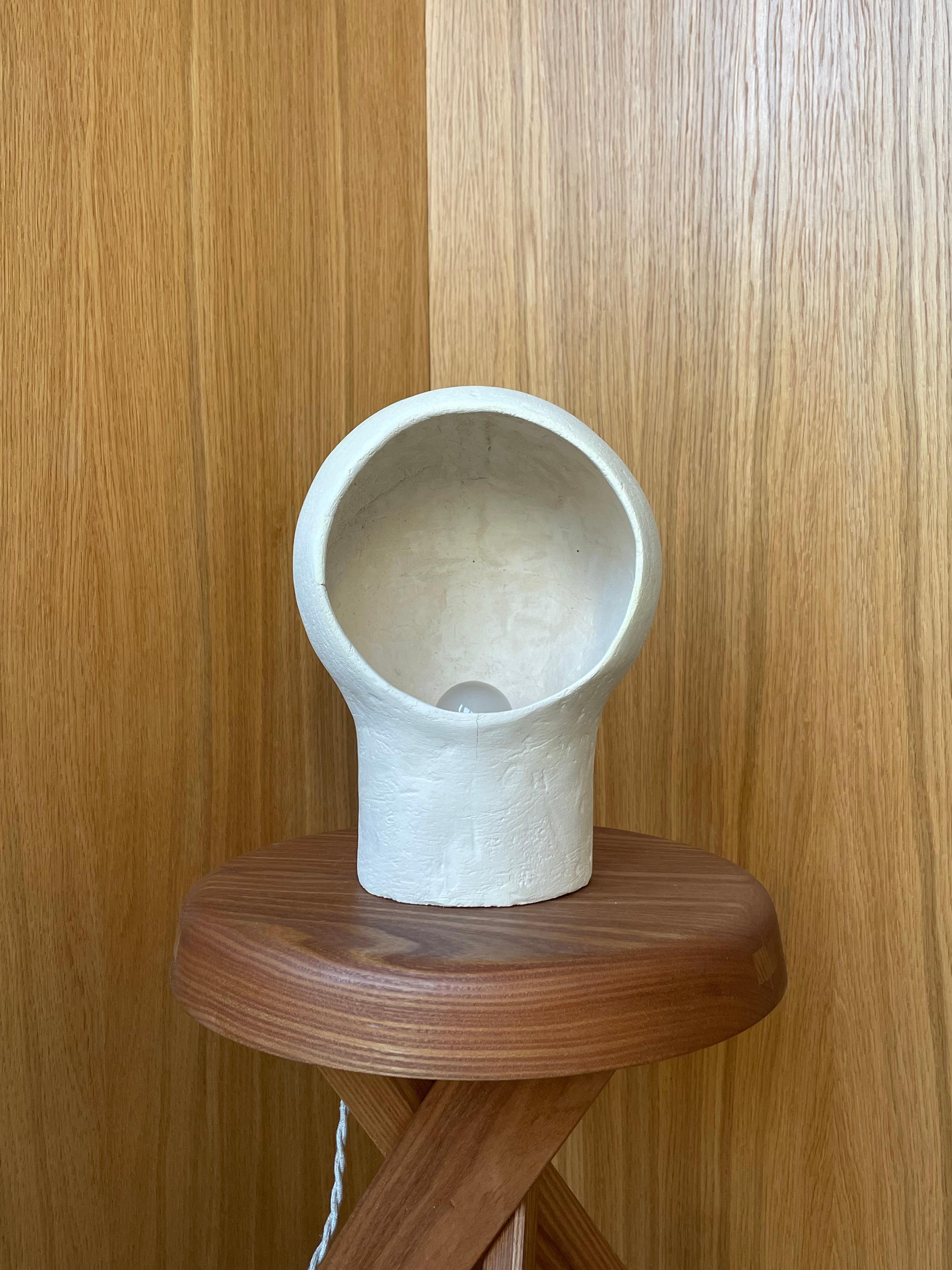 Lampe en grès blanc Nuvole 2 by Renzo Maar
Dimensions :  L 19 x D 15 x H 26 cm
MATERIAL : Céramique (grès blanc), Signé.

Faite d'argile grattée entrecroisée, cette lampe-sculpture ressemble à un nuage, à un nid ou à un casque de plongeur : dans