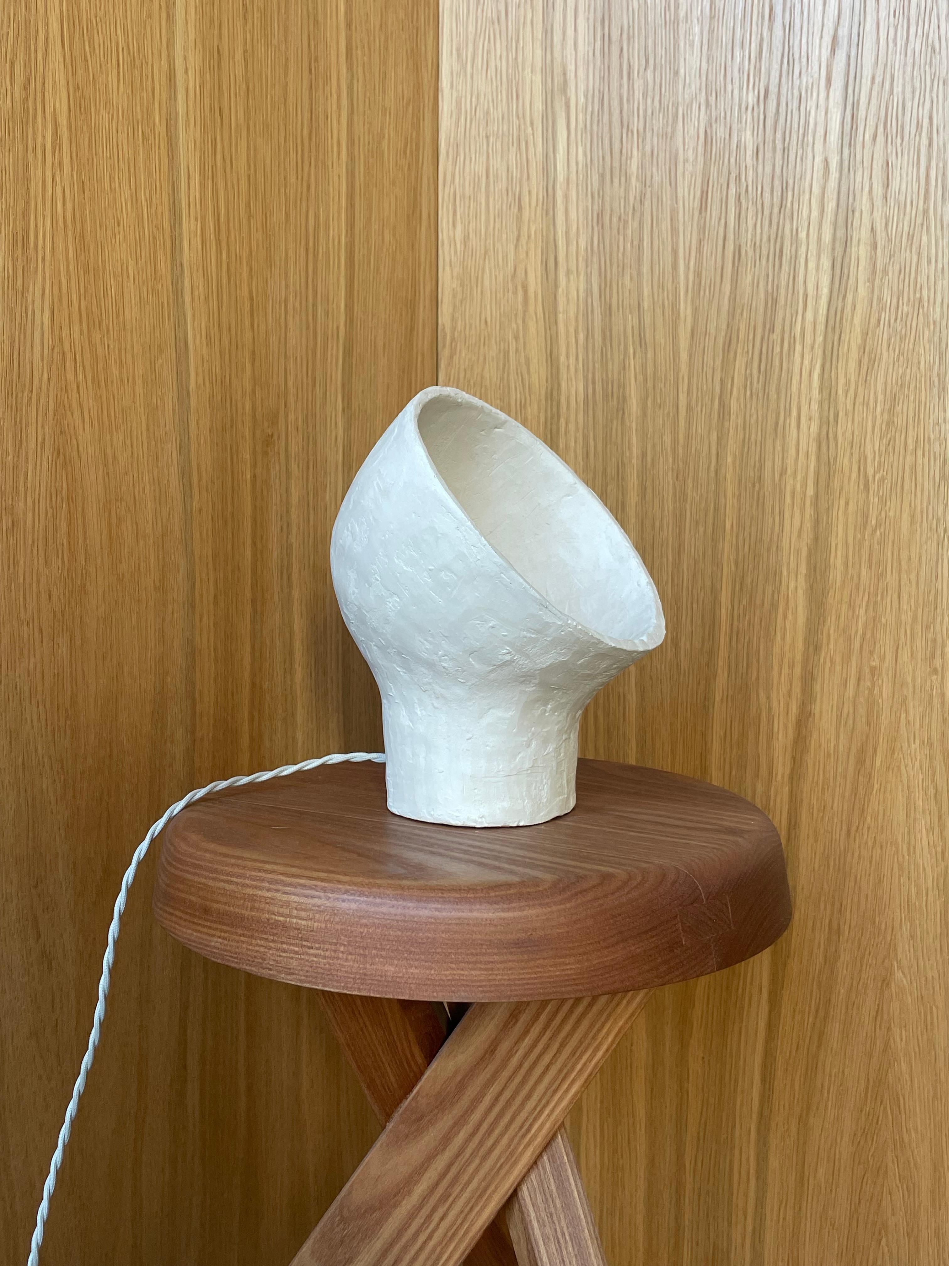 Lámpara de gres blanco Stanza 1 by Renzo Maar
Dimensiones:  An 18 x Pr 16,5 x Al 23 cm
Materiales: Cerámica (gres blanco), Firmado.

Hecha de arcilla rayada entrecruzada, esta lámpara-escultura se parece a una abstracción, a un viejo faro de coche o