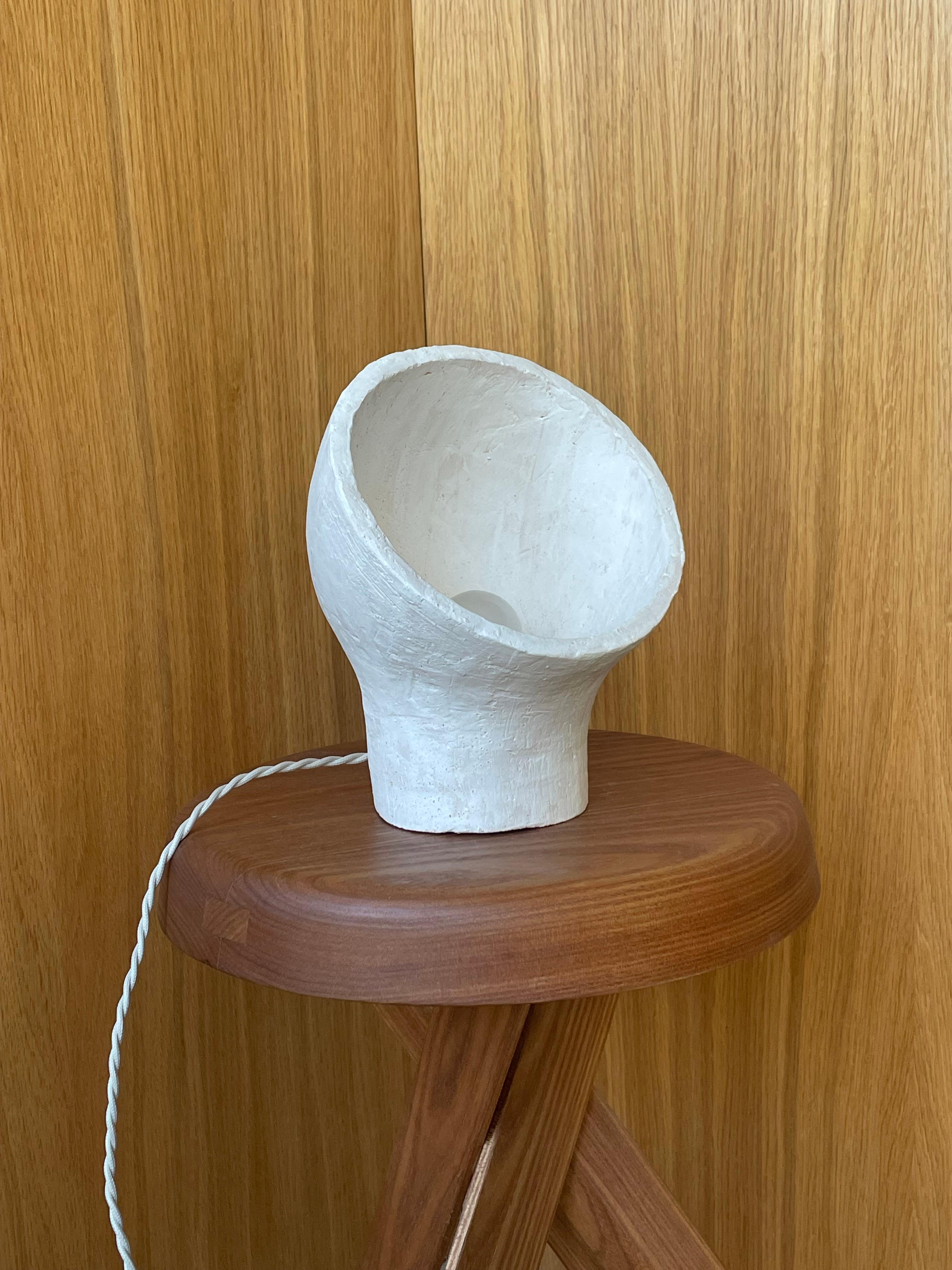 Lámpara de gres blanco Stanza 2 by Renzo Maar
Dimensiones:  An 19 x Pr 17 x Al 23 cm
Materiales: Cerámica (gres blanco), Firmado.

Hecha de arcilla, esta lámpara-escultura se parece a una abstracción, a un viejo faro de coche o a un nido : en