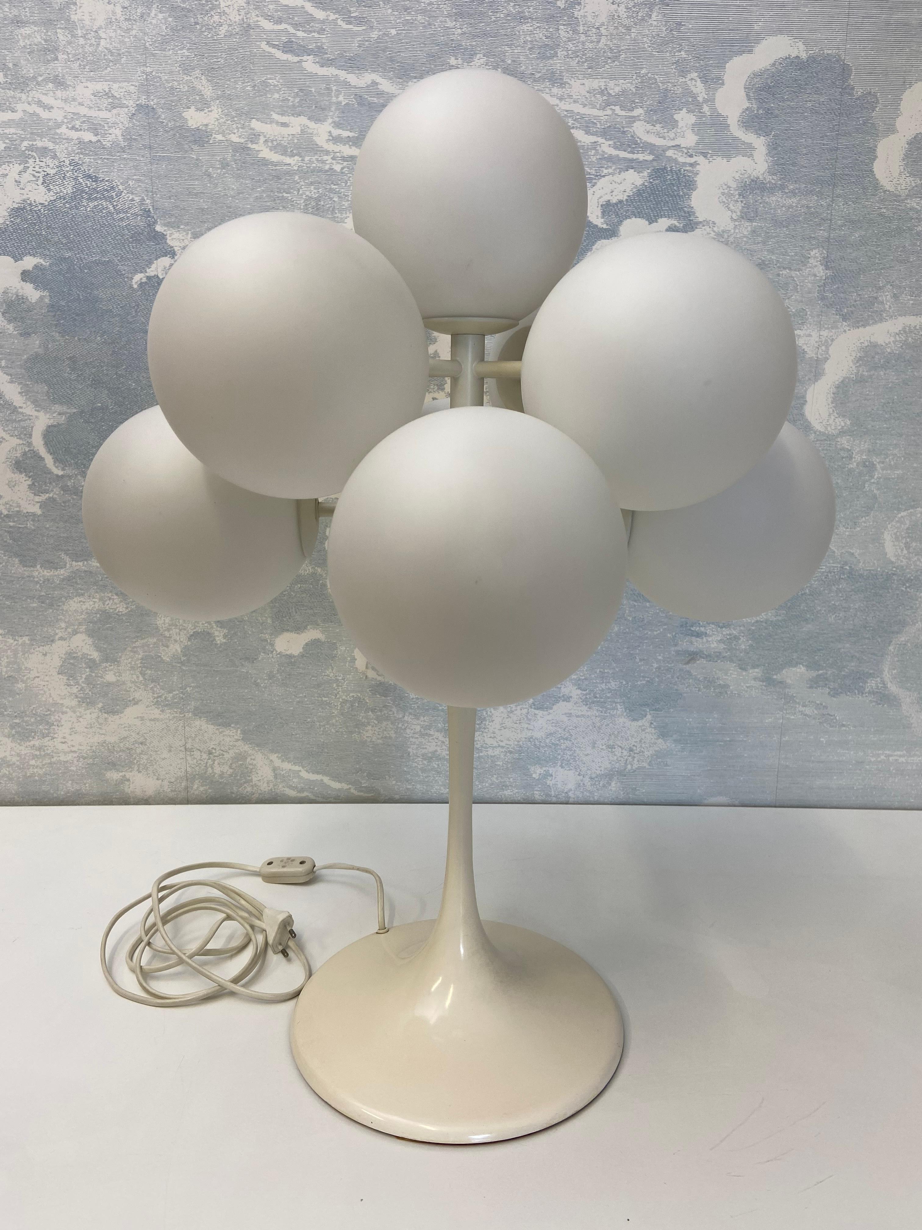 This Space-Age table lamp by the celebrated German designer Eva Renée Nele was made by Temde Leuchten in Switzerland in the 1960s.

Set on a white enameled steel tulip base, eight opal glass globes are arranged at alternating heights on four arms