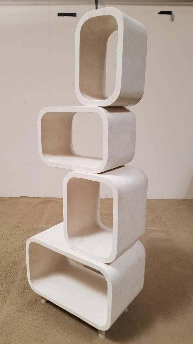 Four stacked, rounded rectangular shapes comprise this bookshelf or étagère. Fully finished on both sides with white tessellated stone over a fiberglass body. Rests on four small stainless steel feet.