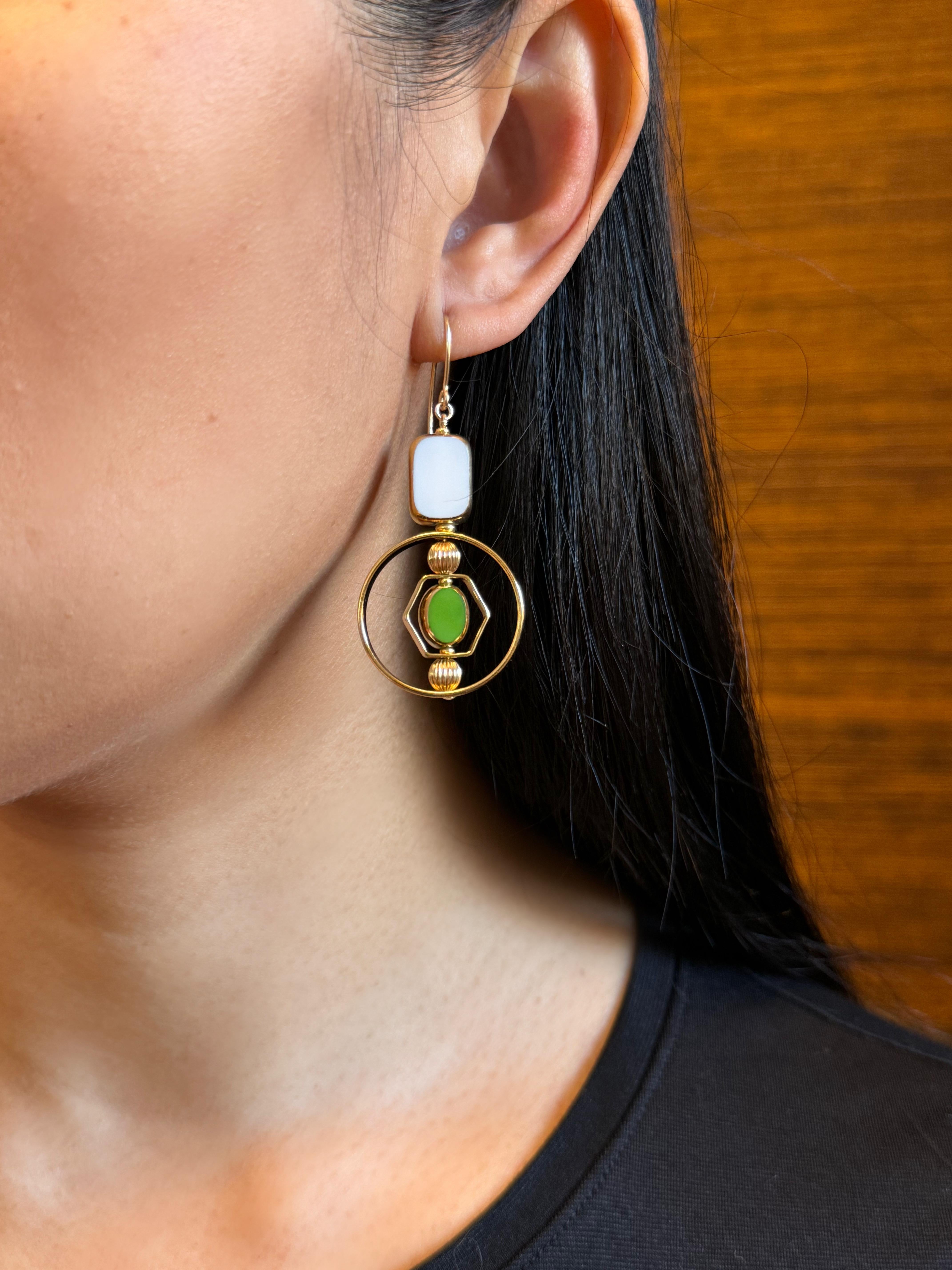 The earrings are light weight and are made to rotate and reposition with movement.

The earrings consist of white tile shape and small green oval-shaped beads. They are new old stock vintage German glass beads that are framed with 24K gold. The