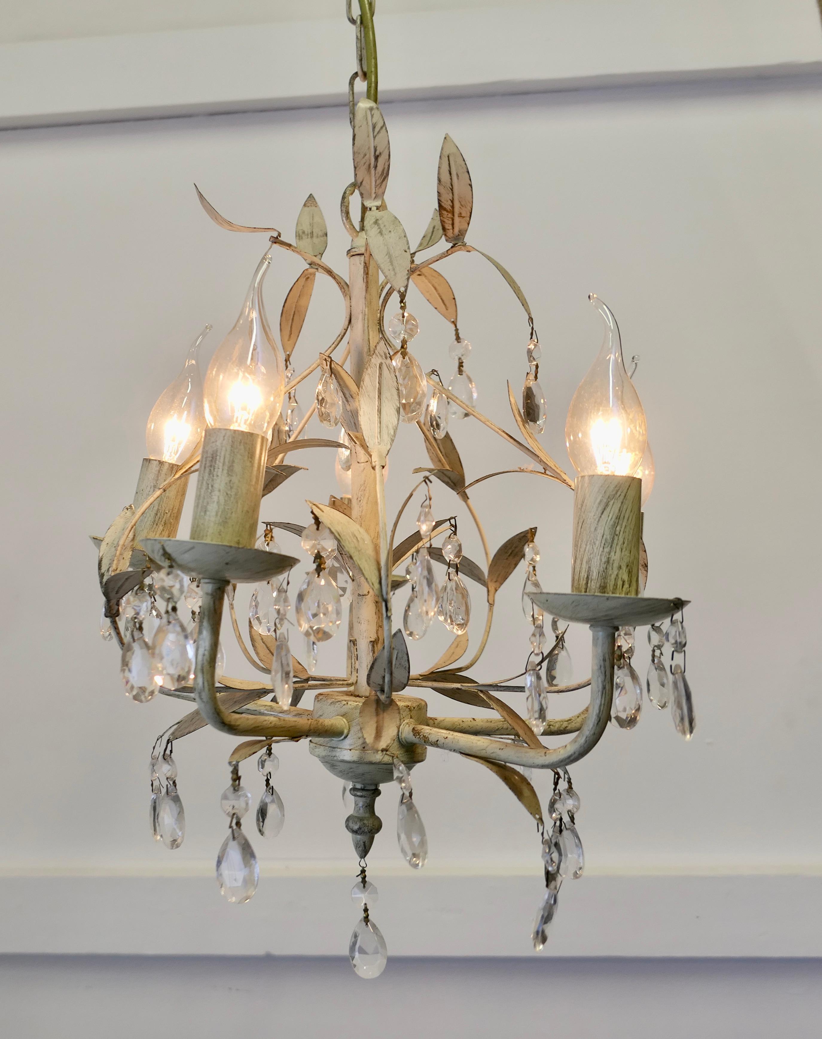  White Toleware Open Basket Ceiling Chandelier 

A decorative circular ceiling light, the light has an open centre and  decorated with toleware leaves in apple white with beautiful faceted pear shaped lusters  
There are 5 bulb holders and a great