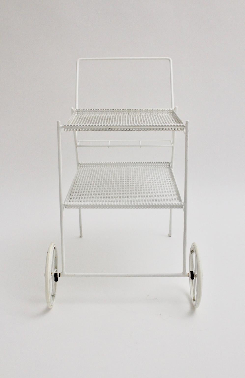 This two tiered bar cart in the style of Mathieu Mategot, circa 1960 consists of wire steel, perforated white coated sheet metal and two wheels covered with white rubber.
The two trays are removable and so very practical to serve drinks or