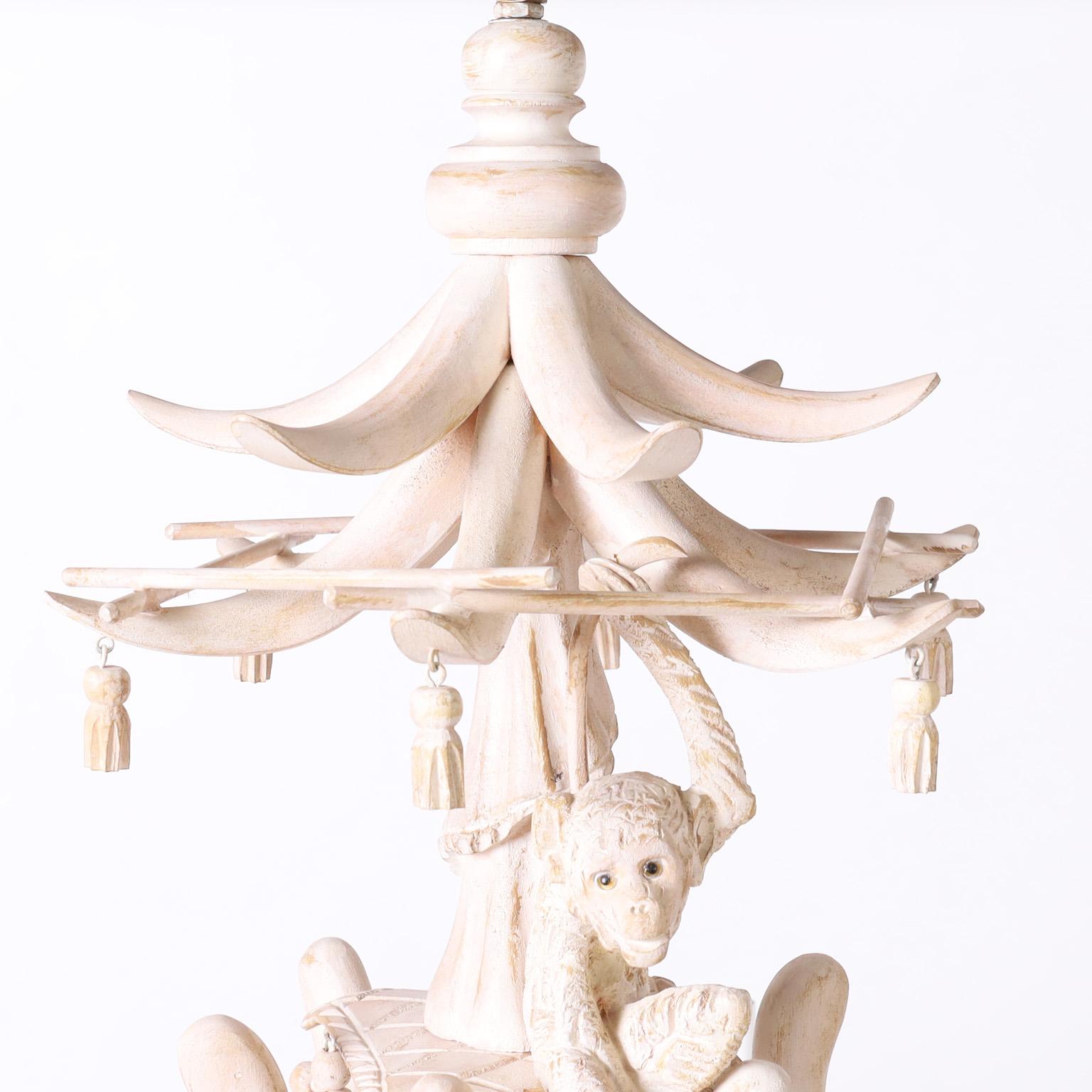 Whimsical vintage chandelier with asian motifs crafted in wood featuring a pagoda form top, carved drapery, wooden tassels, carved monkey, faux bamboo arms and supports and an artichoke finial. One of two similar fixtures.