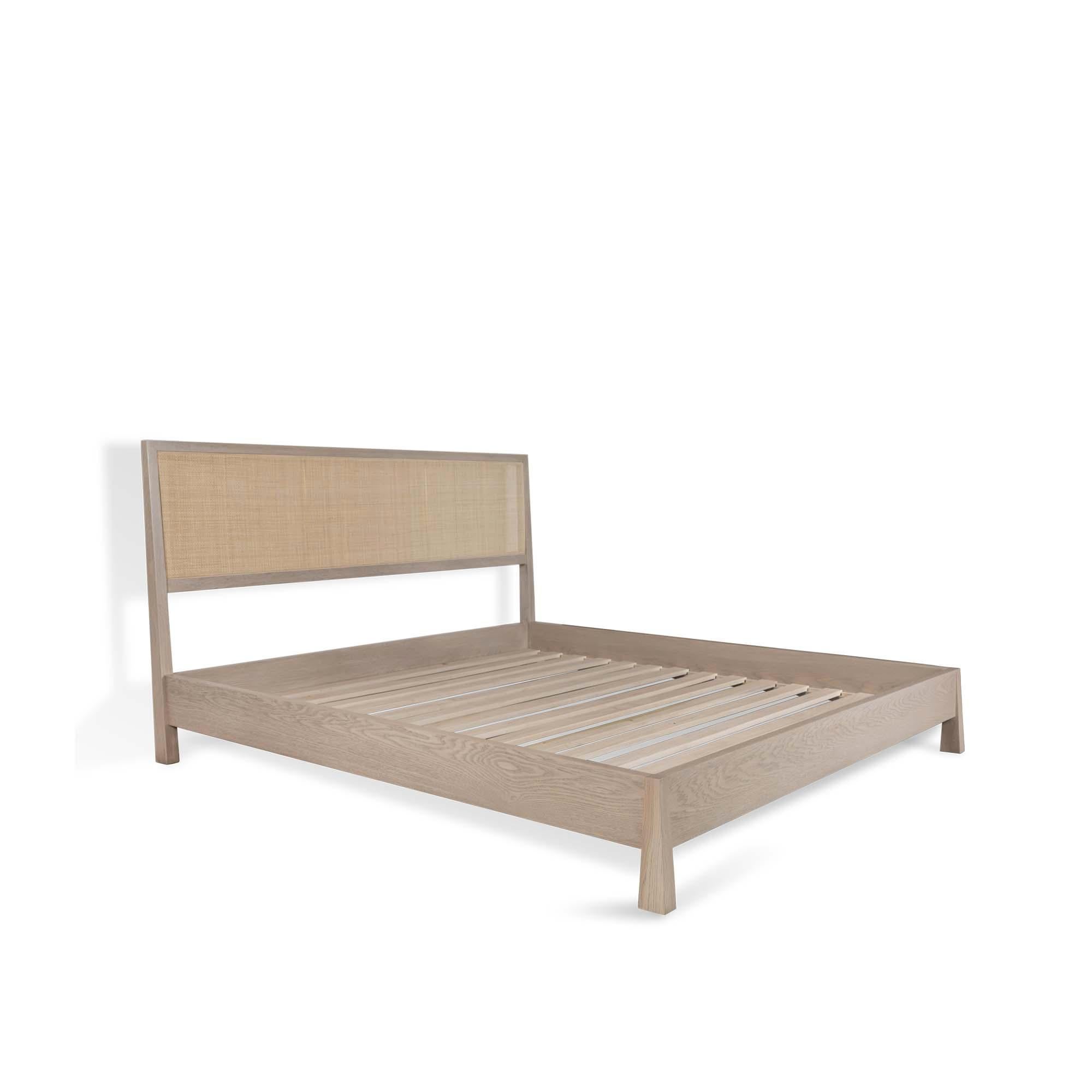 The caned bed is a solid wood framed bed that can be made in either white oak or American walnut. The piece can feature a headboard and footboard or just a headboard made with natural cane inset panels and brass stretchers. Slats are