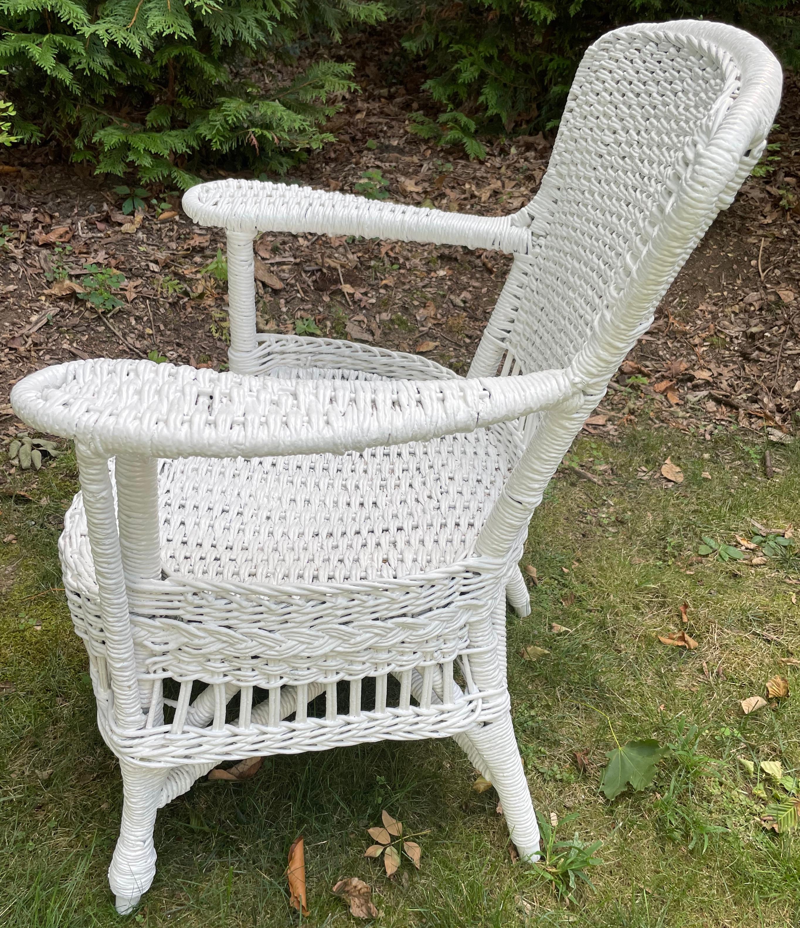 White wicker armchair. Very sturdy vintage American white painted wicker armchair with broad shaped arm rests straight off the classic american porch. United States, 20th Century. 
Dimensions: 25.5” W x 21” D x 32” H; seat is 18” W x 19” D x 15”