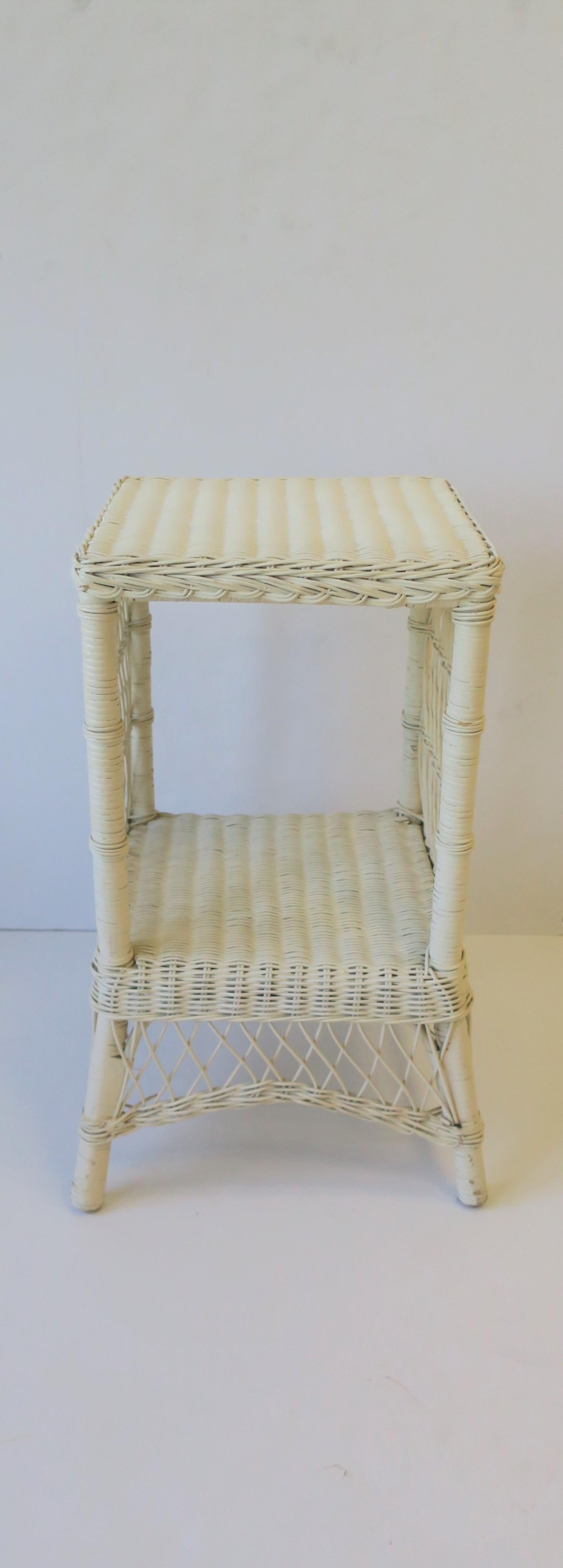 A square white wicker end table or night stand [nightstand] table with lower shelf, circa 1990s. 

Table is a convenient size measuring: 
12.5
