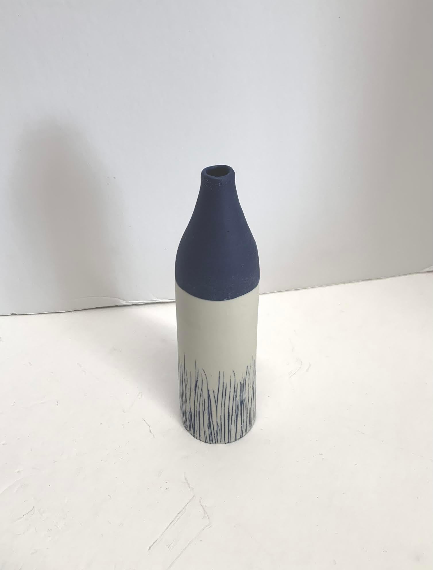 Contemporary Italian hand made ceramic white and blue color block with blue grass blades design thin vase.
Matte glaze.
Part of a large collection of blue and white diminutive vases.
See image #5.