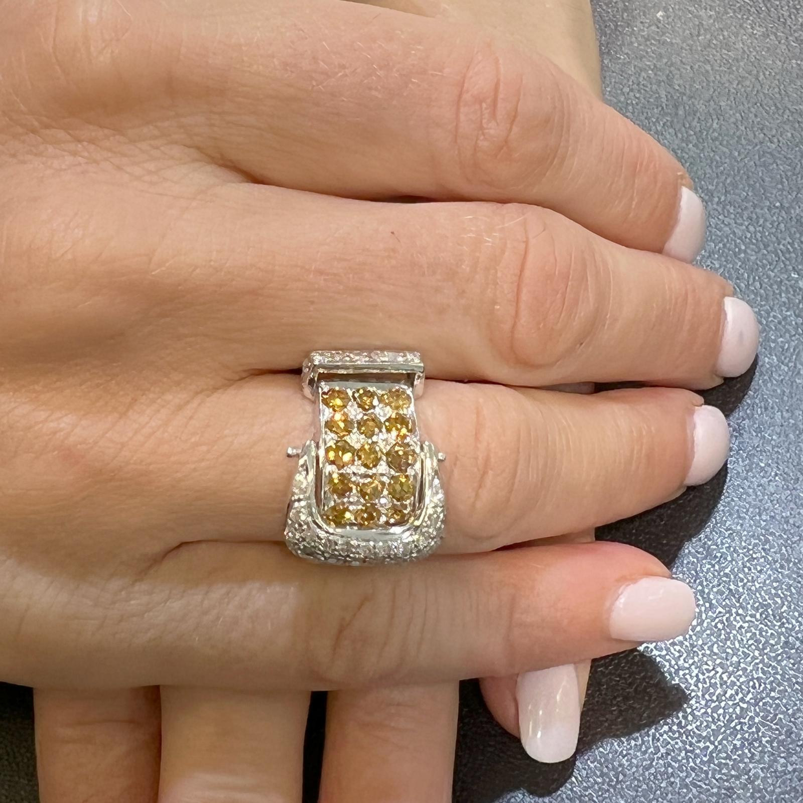 Yellow and white diamond buckle ring crafted in 14 karat white gold. The ring features 18 yellow round brilliant diamonds and 37 white round brilliant cut diamonds weighing approximately 2.20 carat total weight. The white diamonds are graded G-H