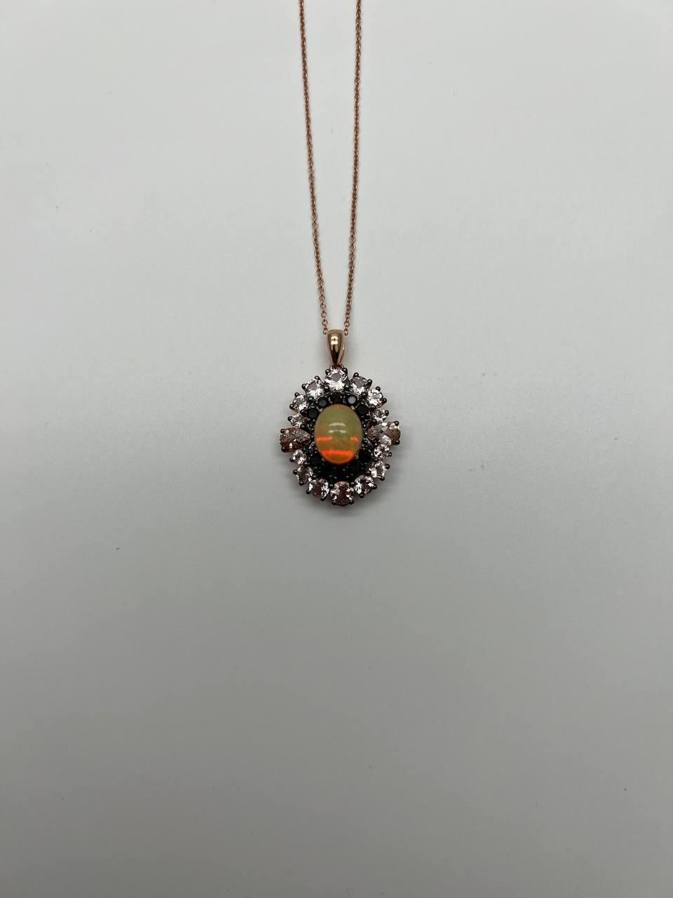 A stunning opal pendant necklace. Set in a delicate chain, this exquisite piece features a central opal gemstone with a captivating play of colors.

The opal is encircled by a halo of sparkling black diamonds and peach morganites, enhancing its