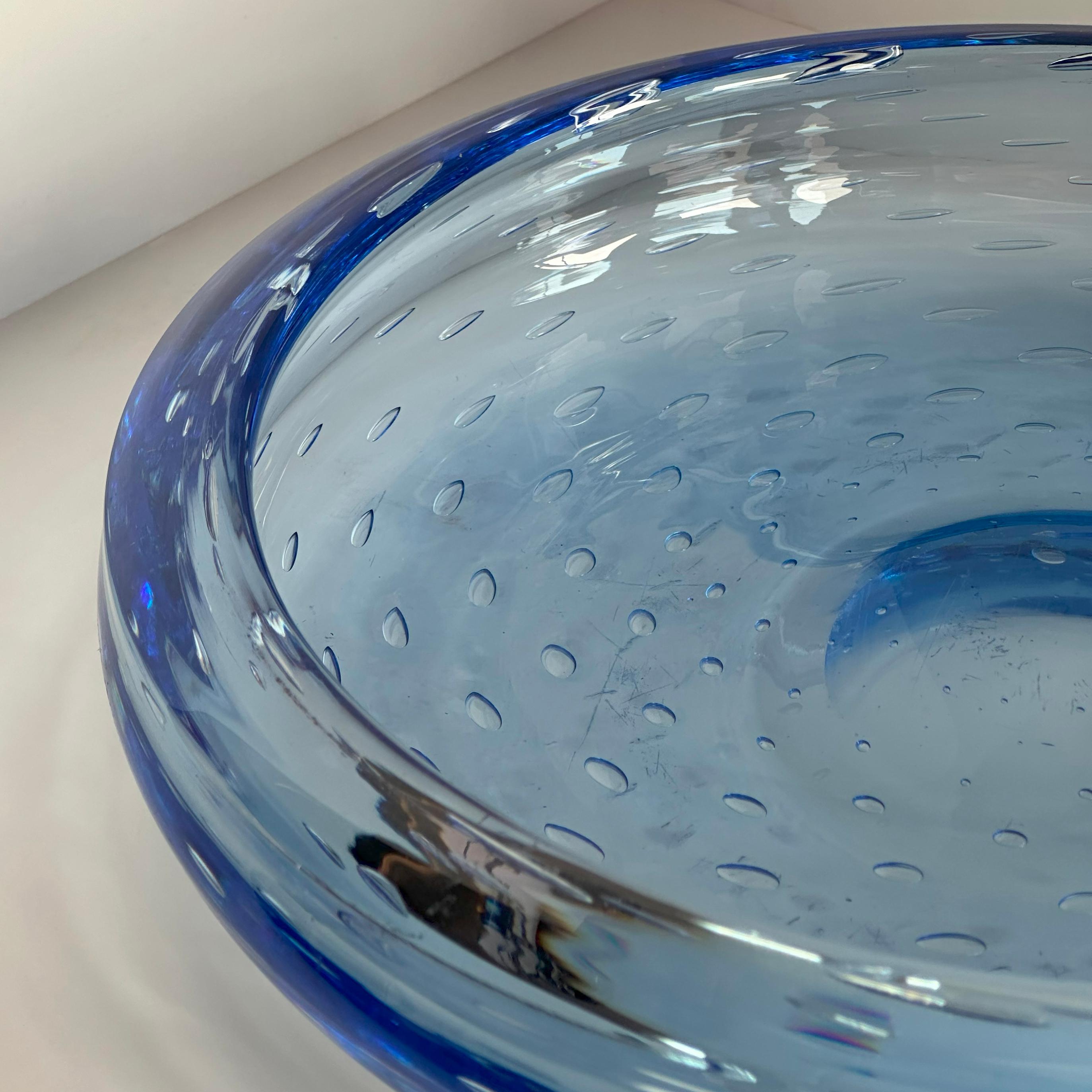 A large blue glass dish by the esteemed English glassmakers Whitefriars, designed by the renowned glass artist Geoffrey Baxter in the 1950s.

The dish features luminous cyan blue glass, punctuated with an array of bubbles arranged in concentric