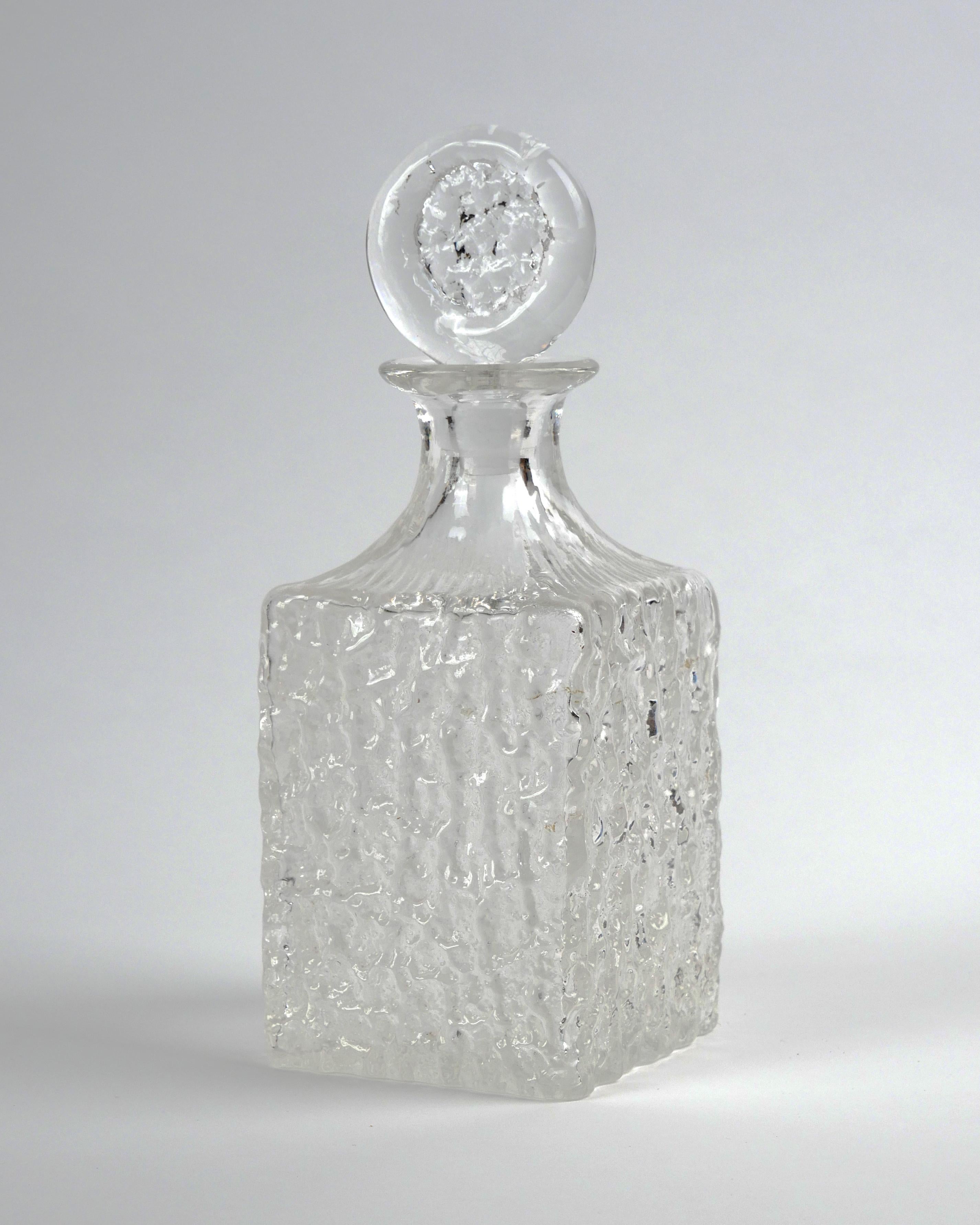 Geoffrey Baxter for Whitefriars, c. 1960s
Decanter from the 'Glacier’ range, model number 9725
Clear textured glass
Excellent condition without damage

Dimensions (approx.): width 10cm, depth 10cm, height 20cm/27cm; weight: 1200g.