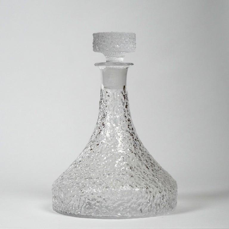 Geoffrey Baxter for Whitefriars, c. 1960s
Decanter from the 'Snowflake’ range, model number 153
Clear textured glass
Excellent condition without damage

Dimensions (approx.): diameter 17cm, height 224.5cm; weight: 1420g