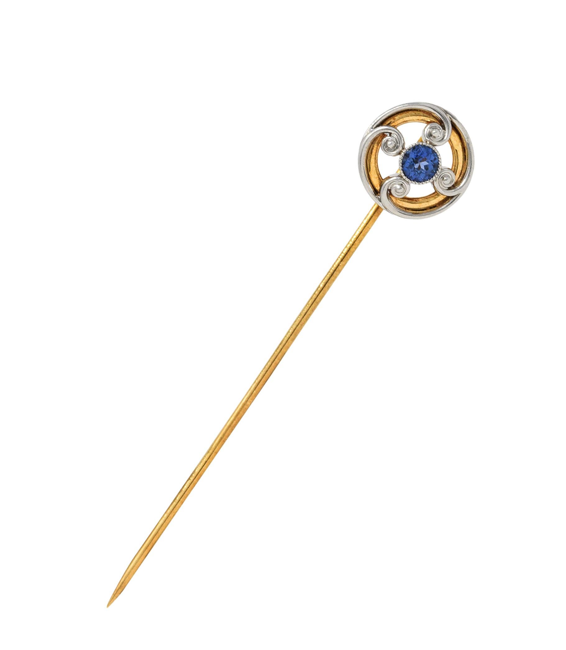 Centering a round cut sapphire weighing approximately 0.30 carat

Very eye-clean and strongly violetish blue in color

Bezel set and surrounded by four scrolling volute motifs

Tested as platinum-topped 14 karat gold

Maker's mark for Whiteside &