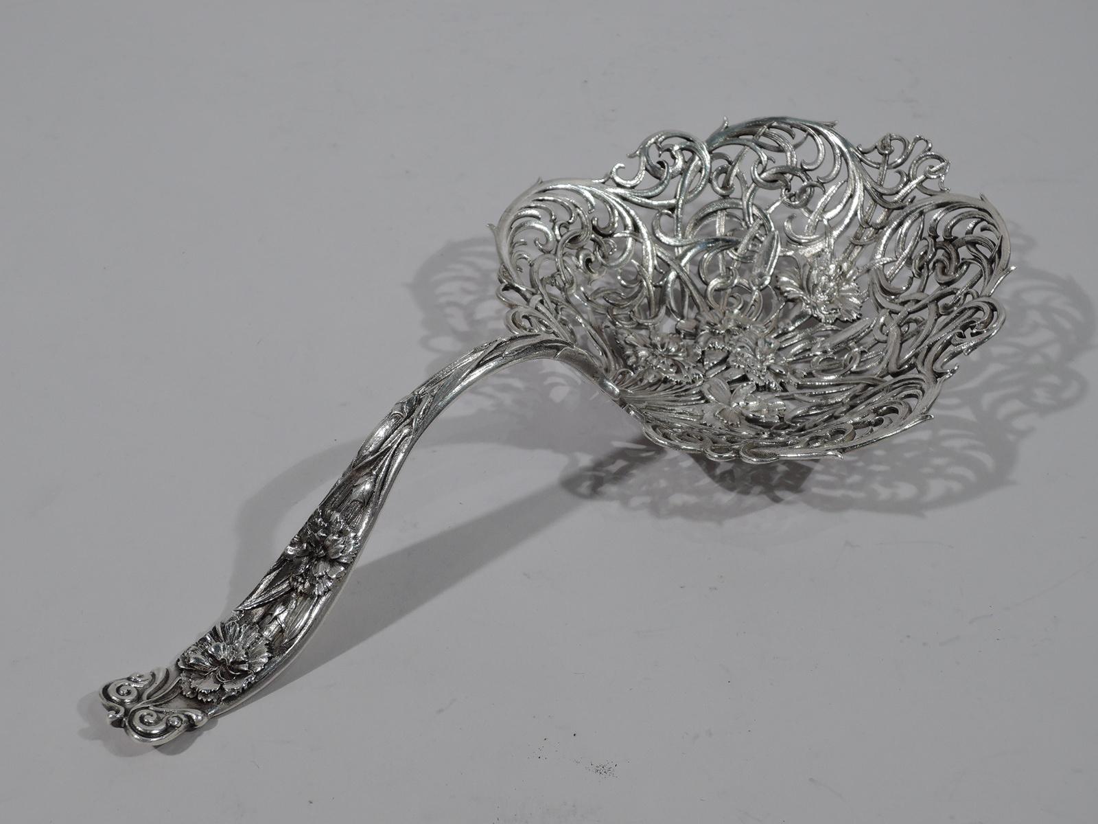 Art Nouveau sterling silver bonbon scoop. Made by Whiting in New York. Large shaped bowl with loose and interlaced scrollwork overlaid with flowers. Handle solid and curved with chased flowers and volute terminal. Turn-of-the-century freshness.