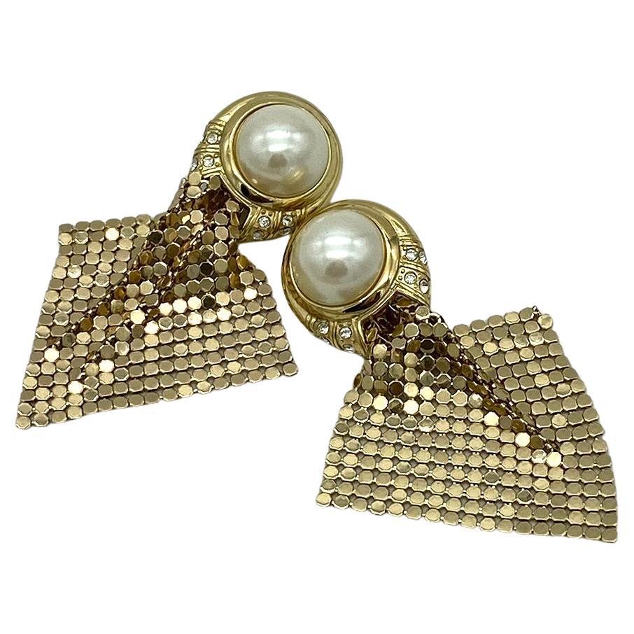 Dies ist ein Paar Whiting & Davis Perle und Mesh Tropfen Ohrringe. Diese goldfarbenen Ohrringe im Art-Déco-Stil haben große simulierte Perlen, die mit klaren Strasspavés verziert sind, und goldene Mesh-Drops.

Unsere Vintage-Schmuckkollektion und