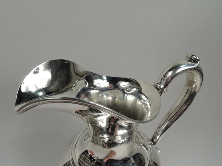Edwardian Classical sterling silver ewer. Made by Whiting in New York in 1912. Ovoid body with helmet mouth, capped s-scroll handle, and raised foot. Reeding. Fully marked including maker’s and retailer’s (JE Caldwell) stamps, no. 5328, date symbol,