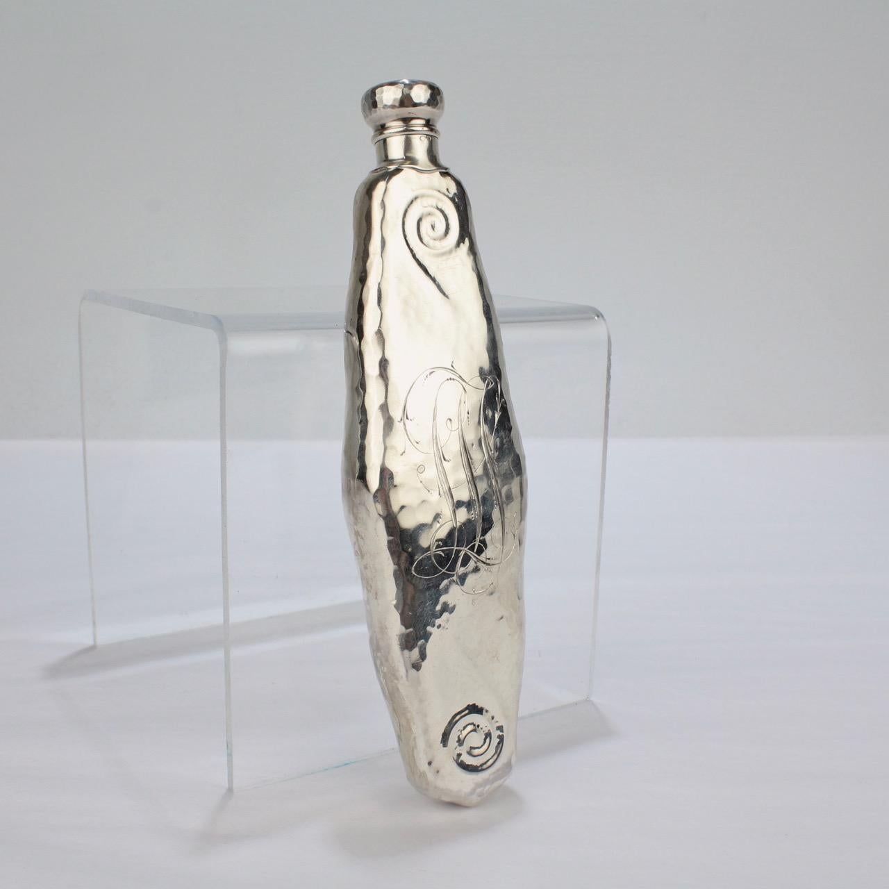 A wonderful, antique sterling silver Art Nouveau flask by Whiting.

With a hand-hammered finish, scalloped sides, swirl decoration to the tops and bottoms, and an etched monogram to the one side.

The base is marked for Whiting, Sterling and with a