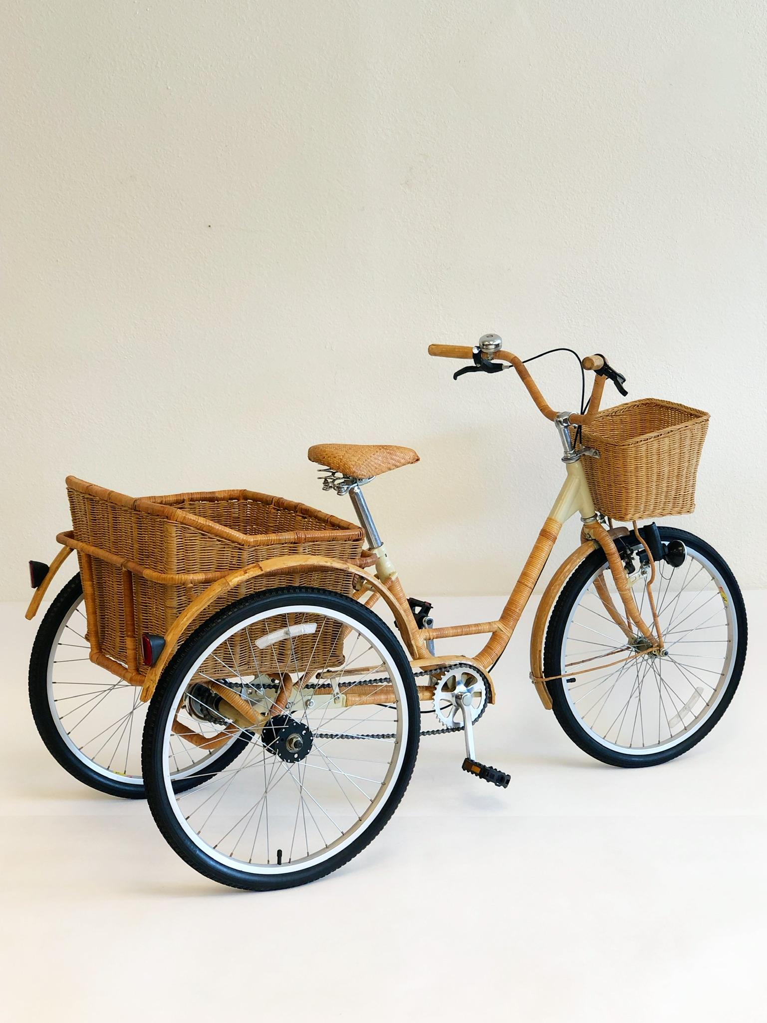A cool 1980s steel frame Adult  tricycle wrapped with wicker and bamboo. The tricycle has a small wicker basket in the front and a removable large wicker basket in the back.
Overall dimensions: 29”deep 72” wide 40.5” high.