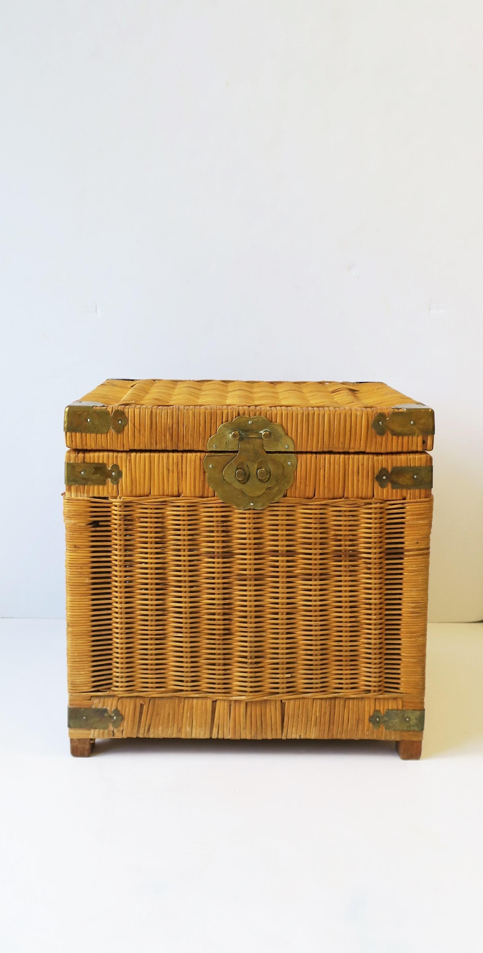 A vintage wicker and brass end table with storage, circa 1970s. This wicker end table 'box' with storage area has decorative brass front closure, corners, edges, and loop handles on two sides. Piece can work as an end or side table. 

Measures: