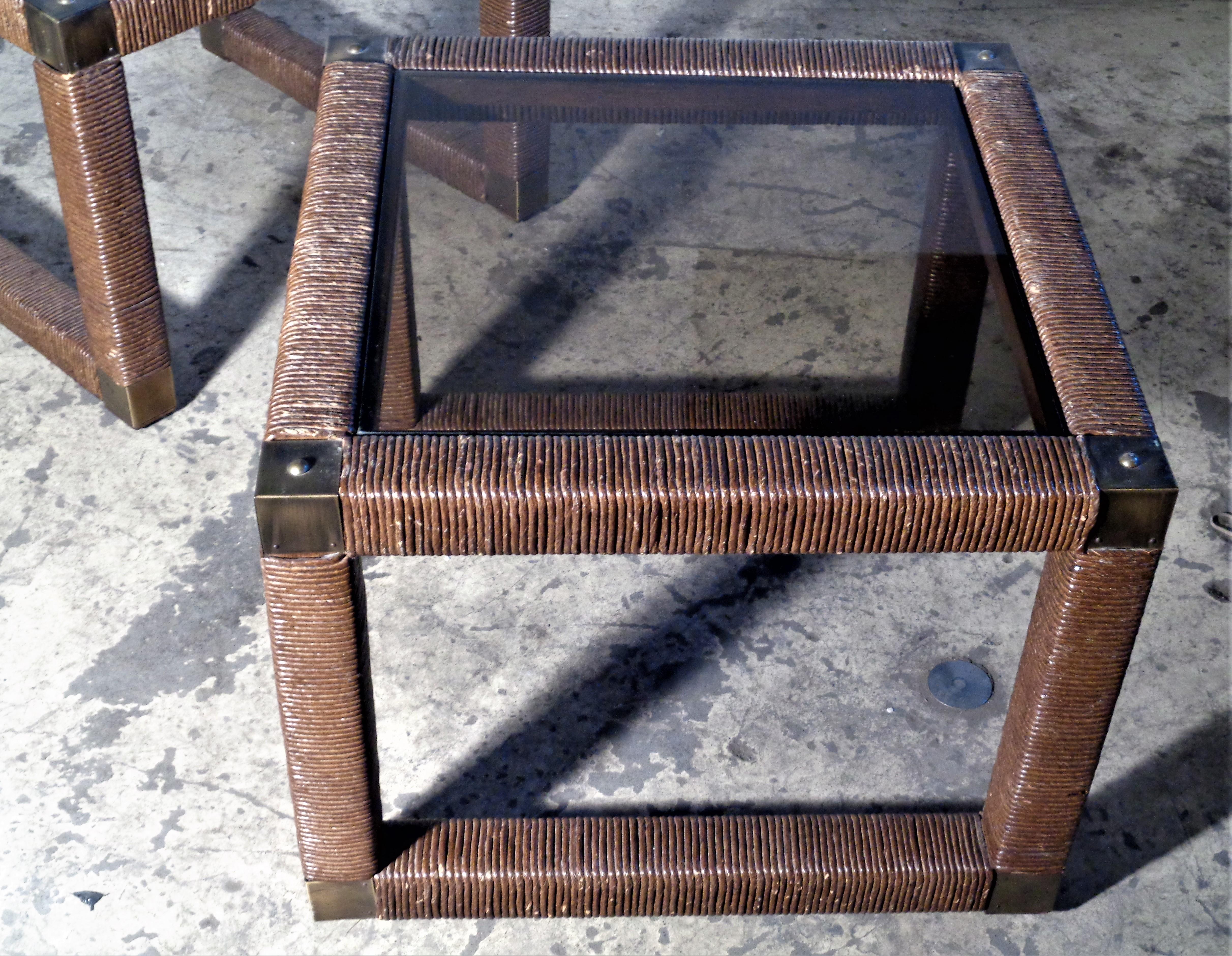 Pair of fiber rush wrapped cube form side tables / end tables with decorative brass fittings at top / bottom corners and recessed smoked glass tops. All original nicely aged vintage condition. Circa 1960. Look at all pictures and read condition