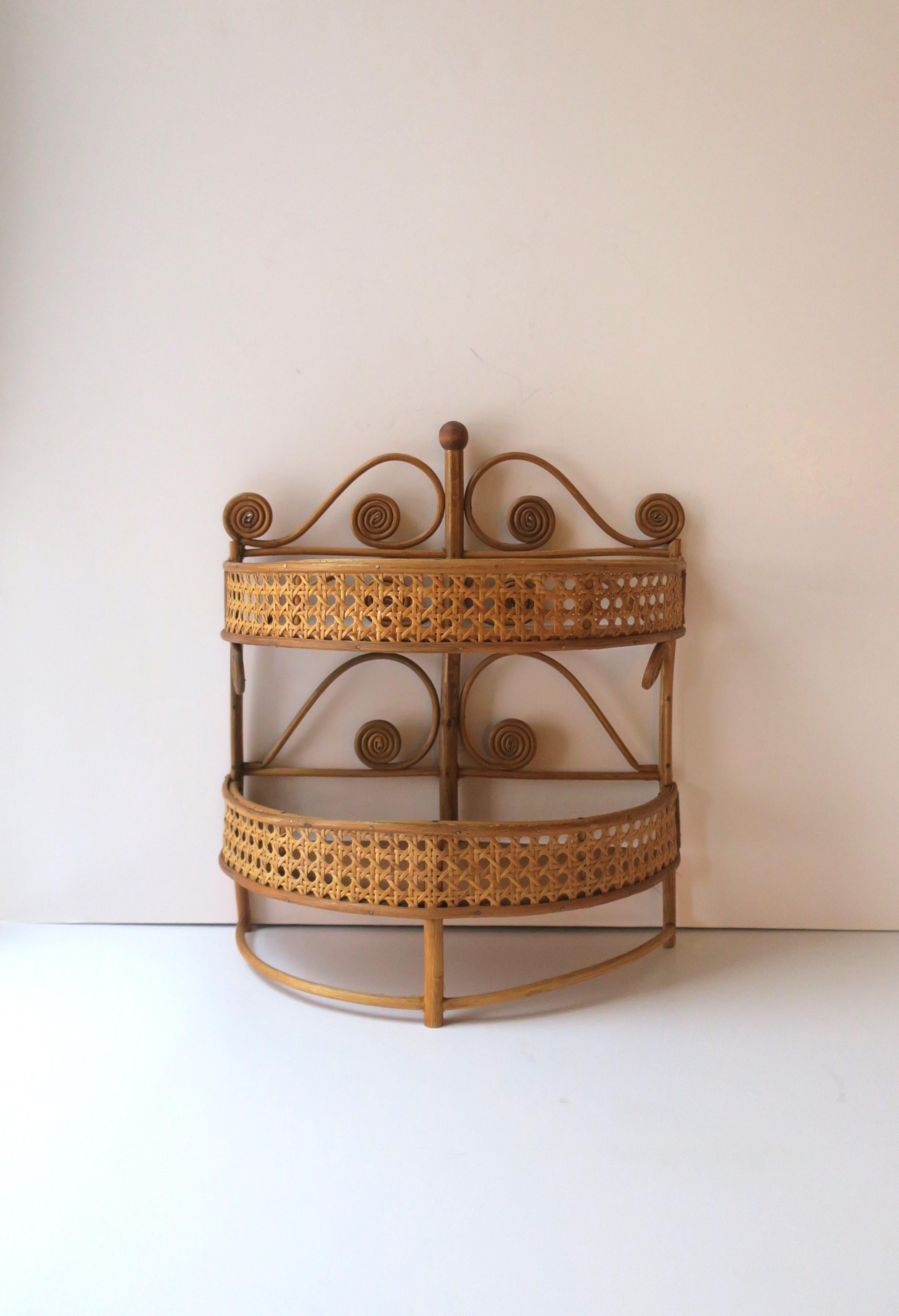 A demi-lune wicker and cane wall shelf, circa mid-20th century. The cane wraps around front in a clean, modern manner, with the bent and curl detail indicating a touch of Victorian and Art Nouveau styles. Piece has two shelves for storage. Piece is