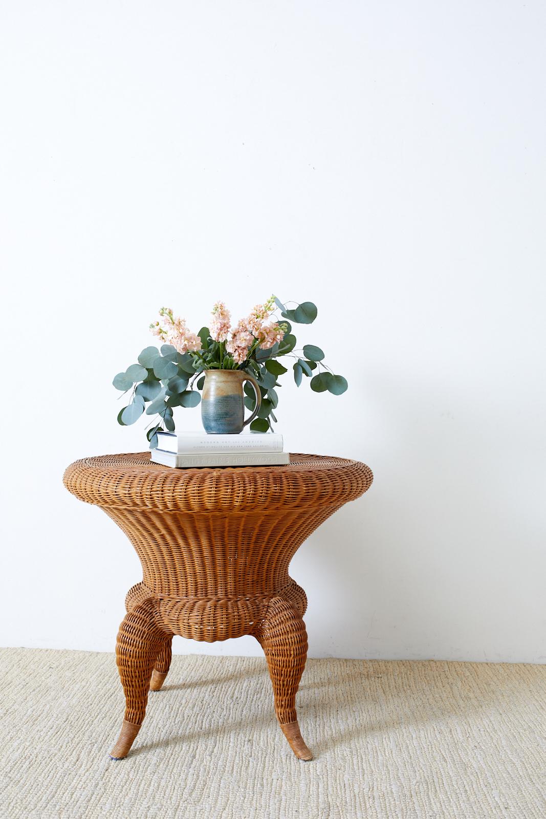 Charming round occasional table or center table made of a rattan frame covered with wicker. The table has a unique waisted hourglass form with whimsical tapered cabriole legs. The top could support a round glass top and be used as a dining or drinks
