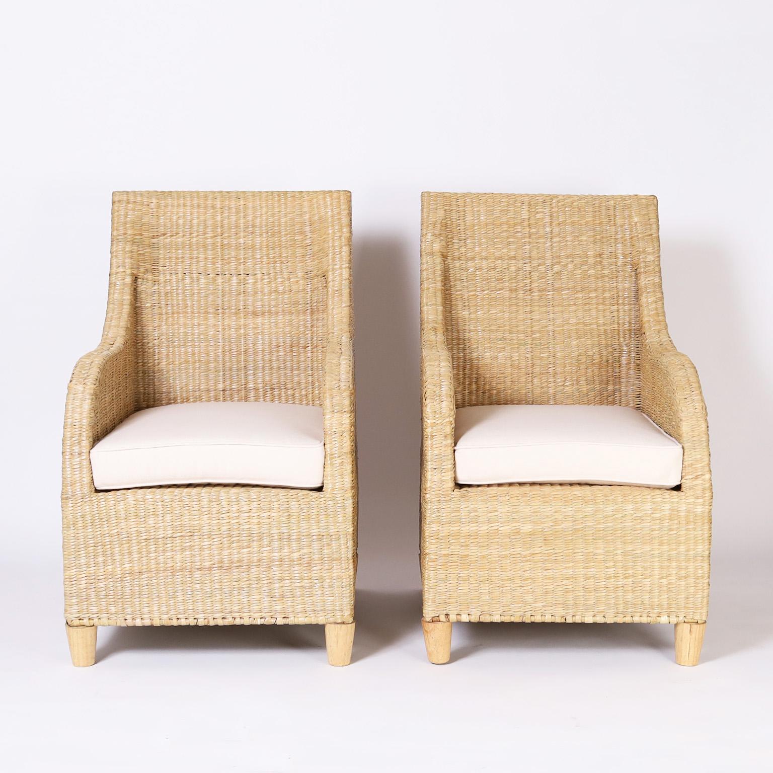 Pair of mid century inspired armchairs crafted in wicker or reed ambitiously woven over a sturdy metal frame. One of many new designs from the FS Flores Collection, offered exclusively by F.S. Henemader Antiques. Priced per chair.