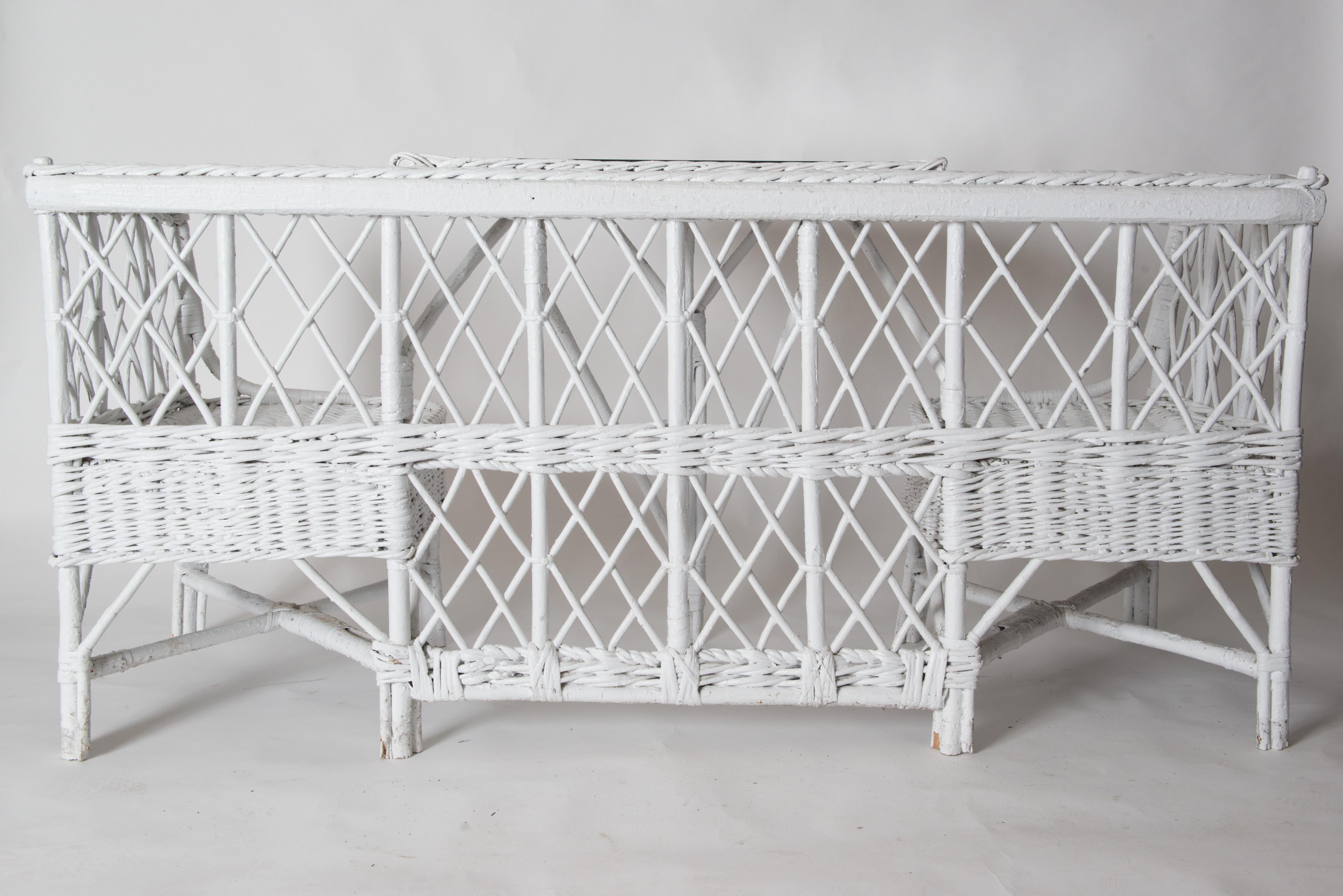 Very rare vintage wicker/reed banquette or booth. One wicker piece includes two corner chairs and an attached wicker table with a protective glass top. A very fun unique piece for a porch, a playroom, a pool house, anywhere you want a conversation