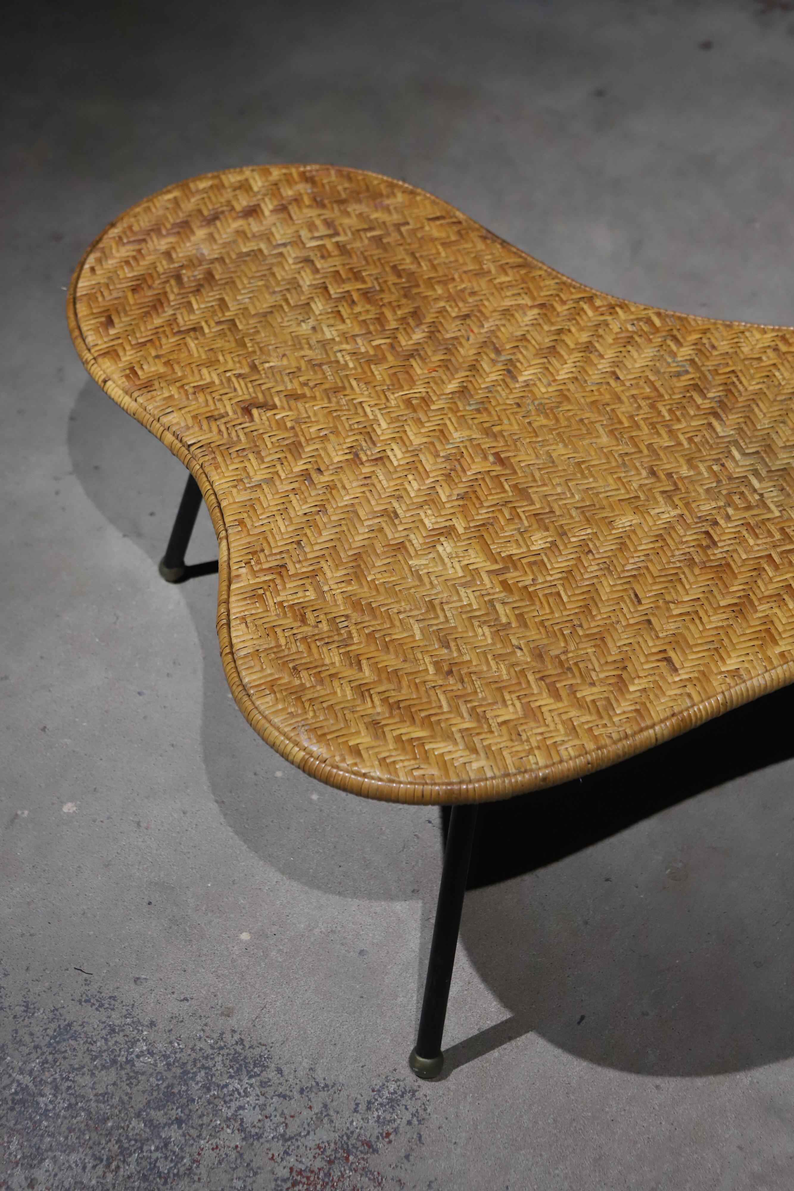 Playful midcentury freeform three-legged wicker cocktail table.