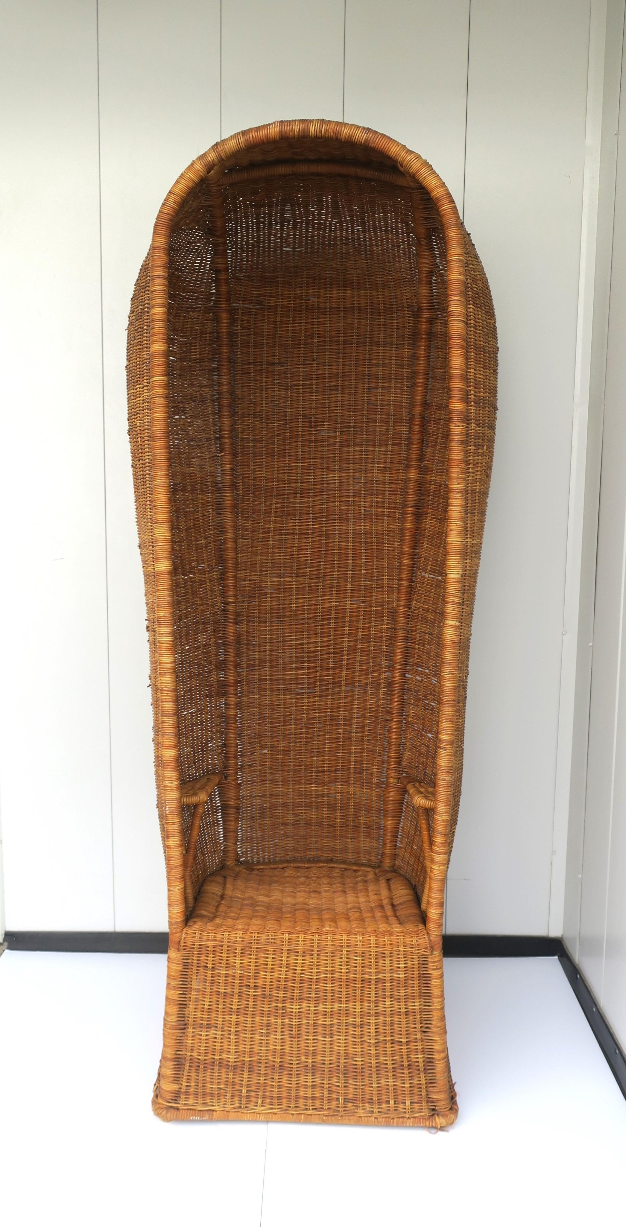 A beautiful and rare wicker hooded canopy chair, Bohemian, circa 1960s, 1970s. Chair is entirely wicker, with wicker arm rests, finished with a simple round seat cushion (seat cushion is removable as shown in images.) This chair makes an impression.