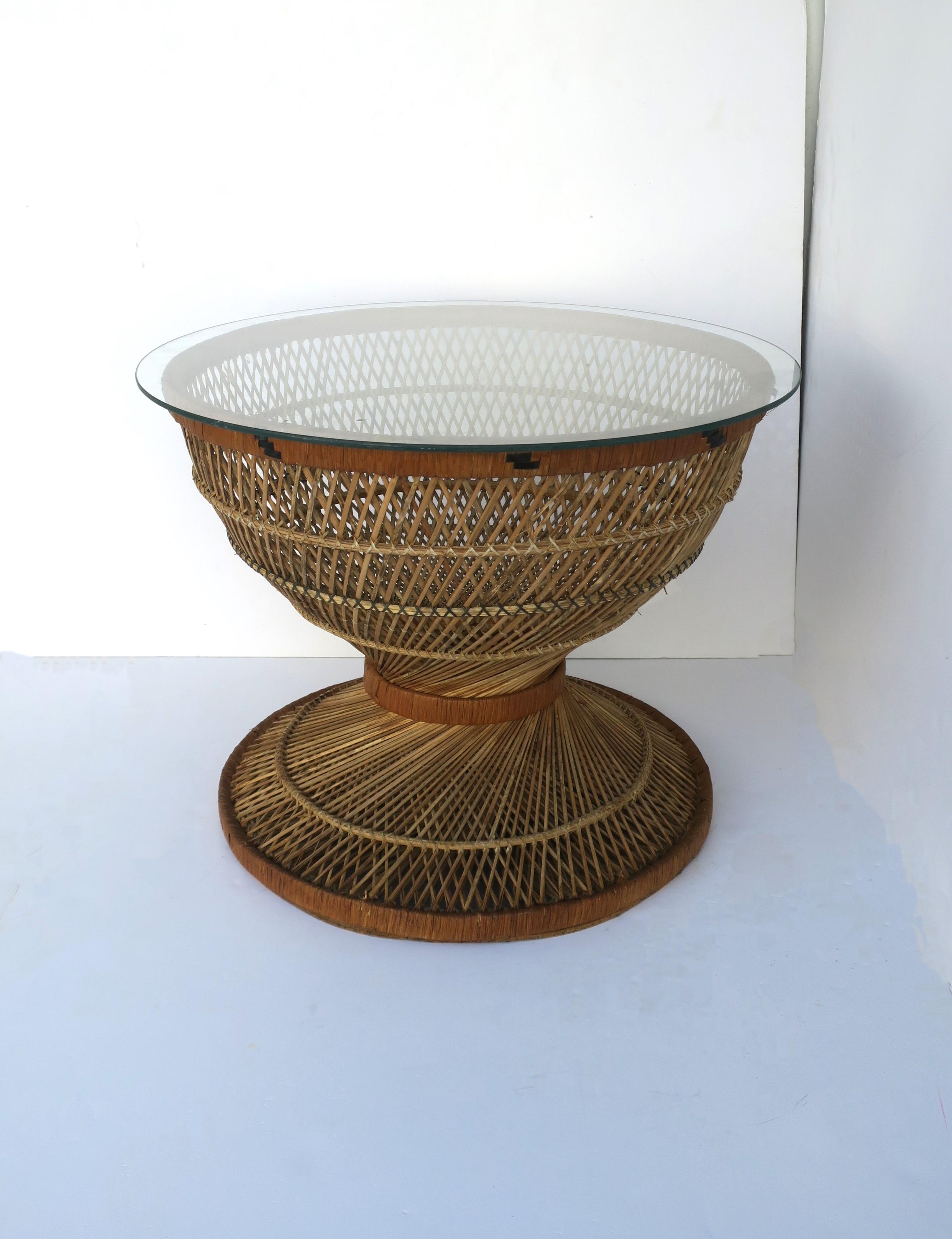 A round wicker and glass end, side or cocktail table with hourglass shape, in the style of designer Emmanuelle Peacock, Bohemian, circa mid-20th century. A round wicker cocktail table with an exaggerated hourglass shape and finished with a glass