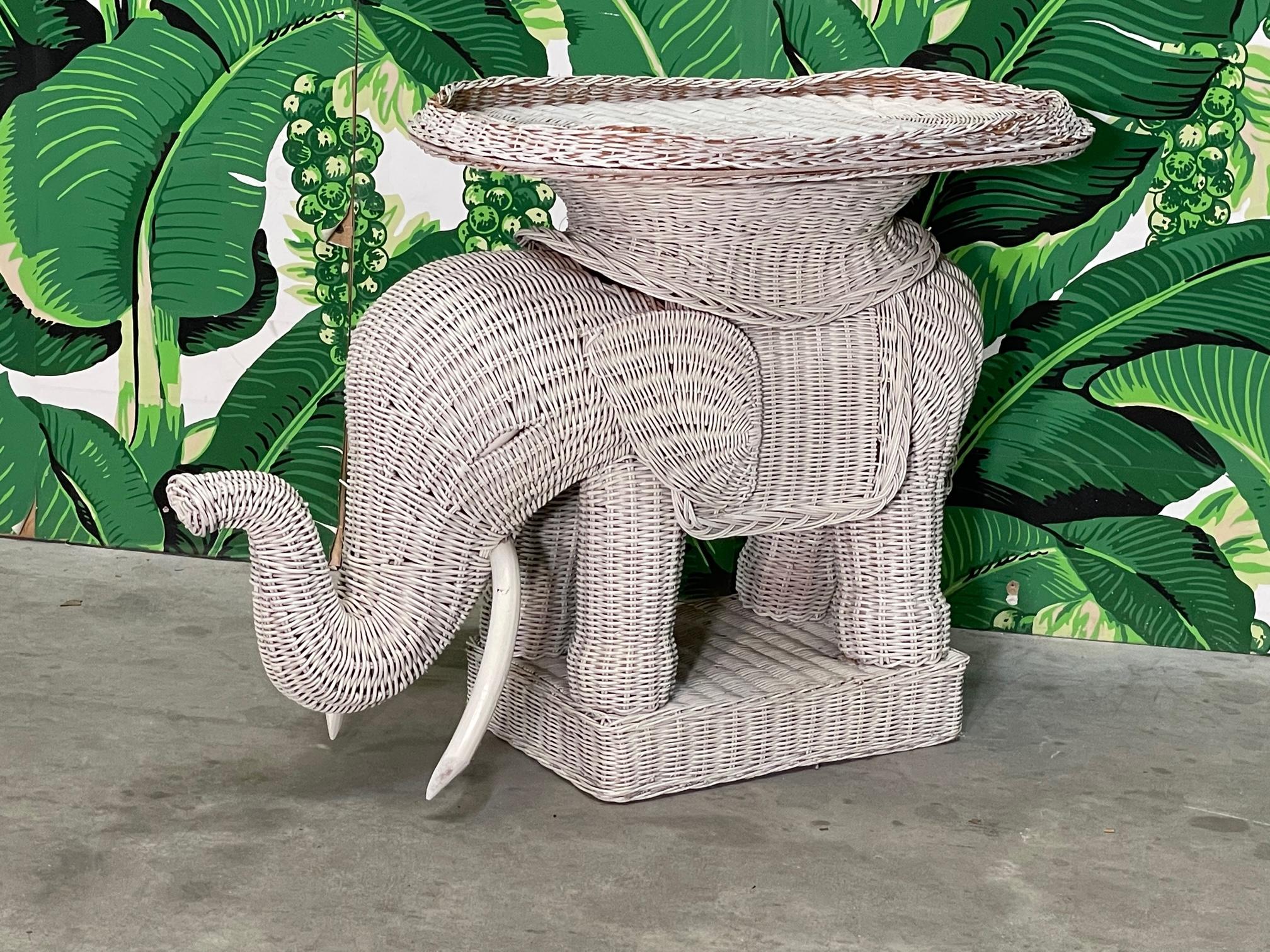 Charming wicker elephant features wooden tusks and a removable top tray. In the style of Mario Lopez Torres. Can be used as an end table or remove the tray to exhibit a wicker version of a garden seat/stool. Good condition with imperfections